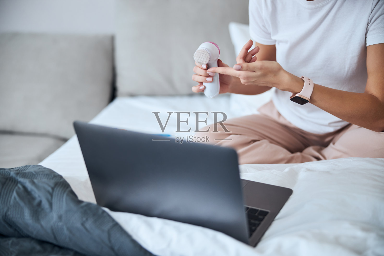 美丽的女人在家用衣服工作在笔记本电脑，同时展示新的照片摄影图片