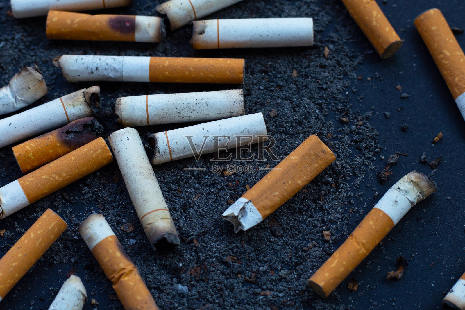 烟灰缸在深色背景上的香烟。照片摄影图片