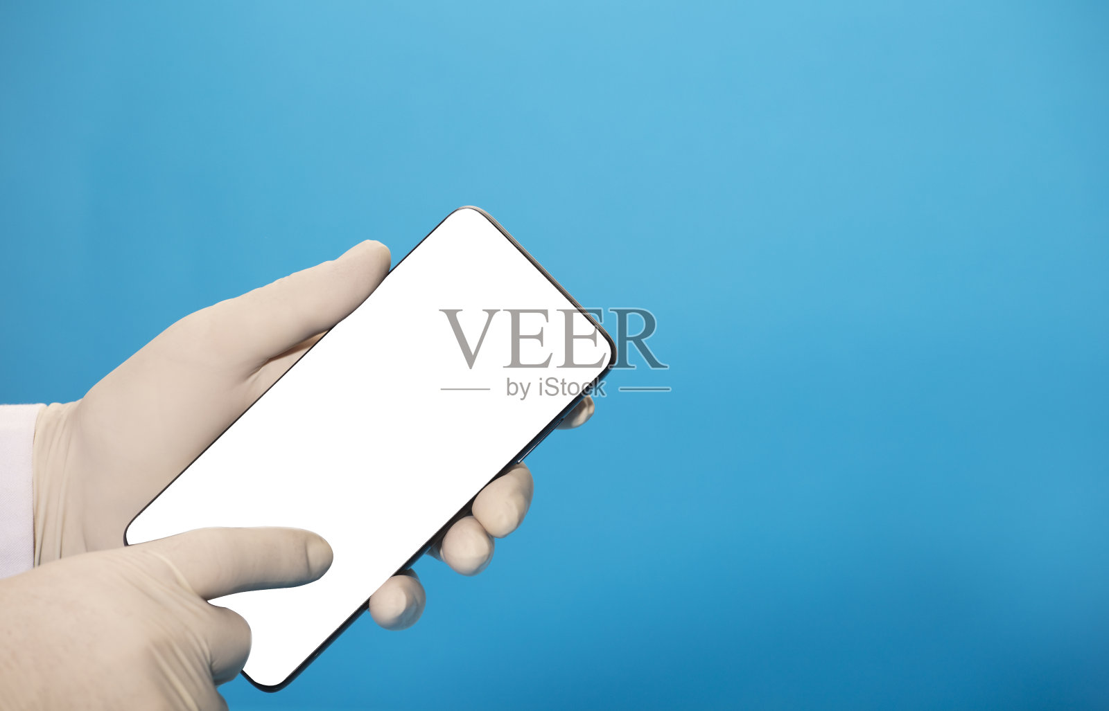 电话与空白屏幕模型(文字或图像)，在医生手中与卫生手套，食指指向手机屏幕(电话注意和协助)，与一个蓝色的背部照片摄影图片