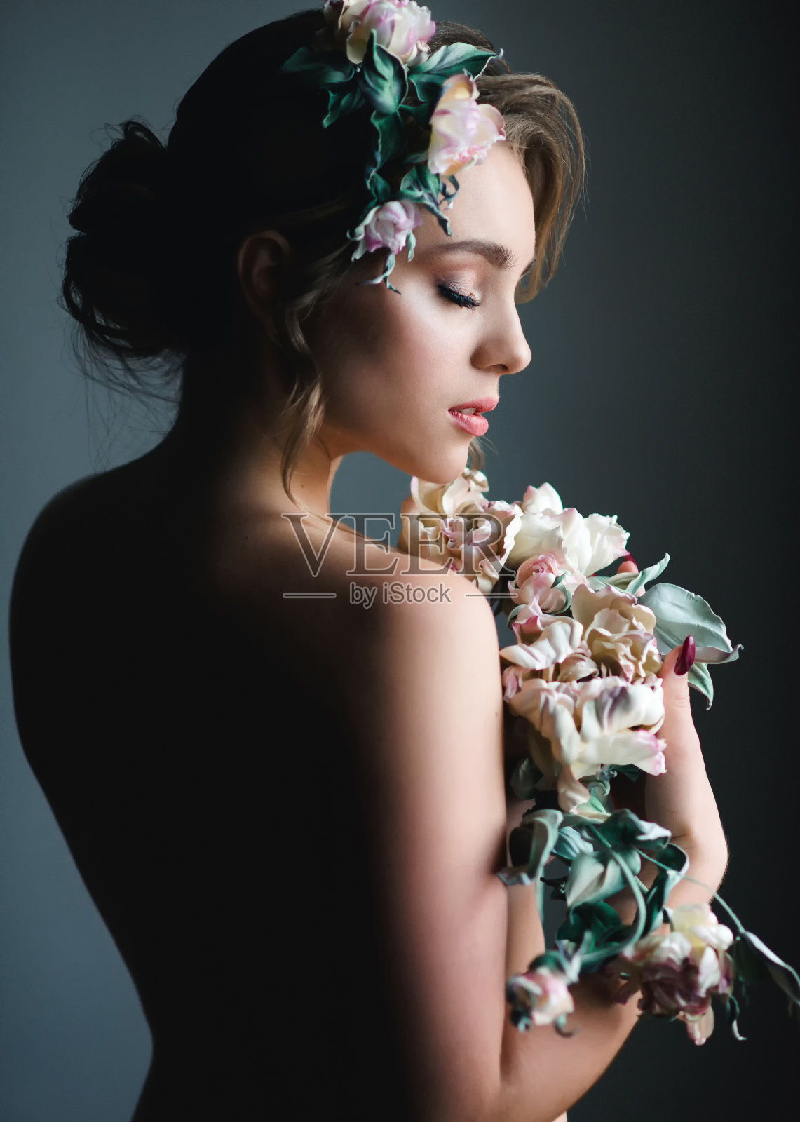 手持鲜花的漂亮女人。美丽的肖像模特与创意的化妆和发型与温柔的花束照片摄影图片