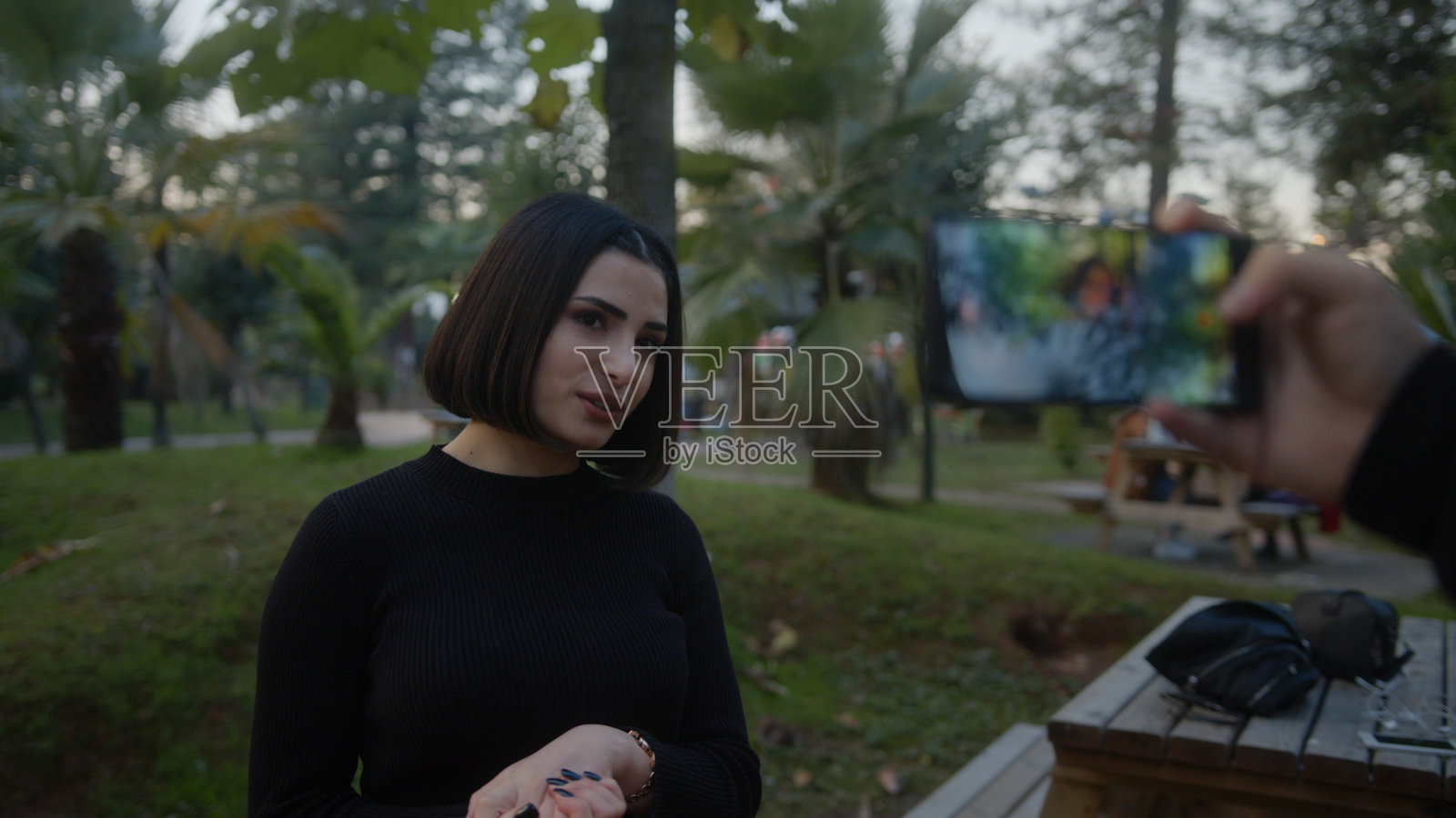 美丽的微笑时尚博主女人在网上新的视频博客，视频博客，与她的智能手机在自然背景。在会议通话记录中，影响者对着摄像机讲话照片摄影图片