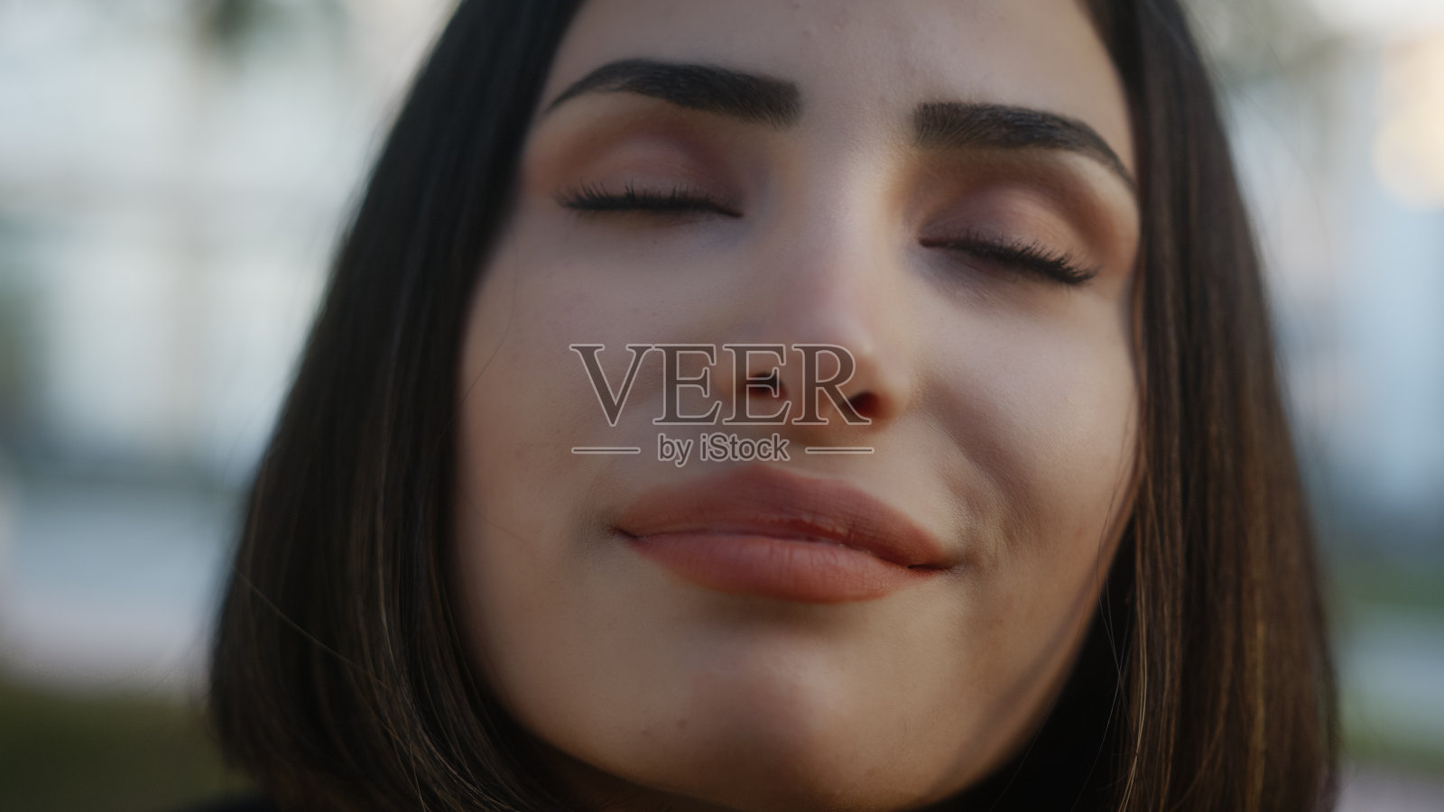 街上闭着眼睛，面带微笑的年轻女子面部特写照片摄影图片
