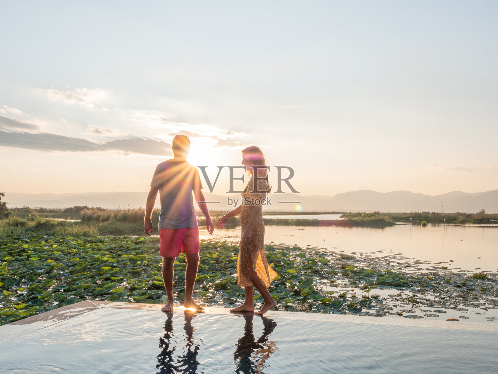 一对夫妇在泳池边看日落照片摄影图片