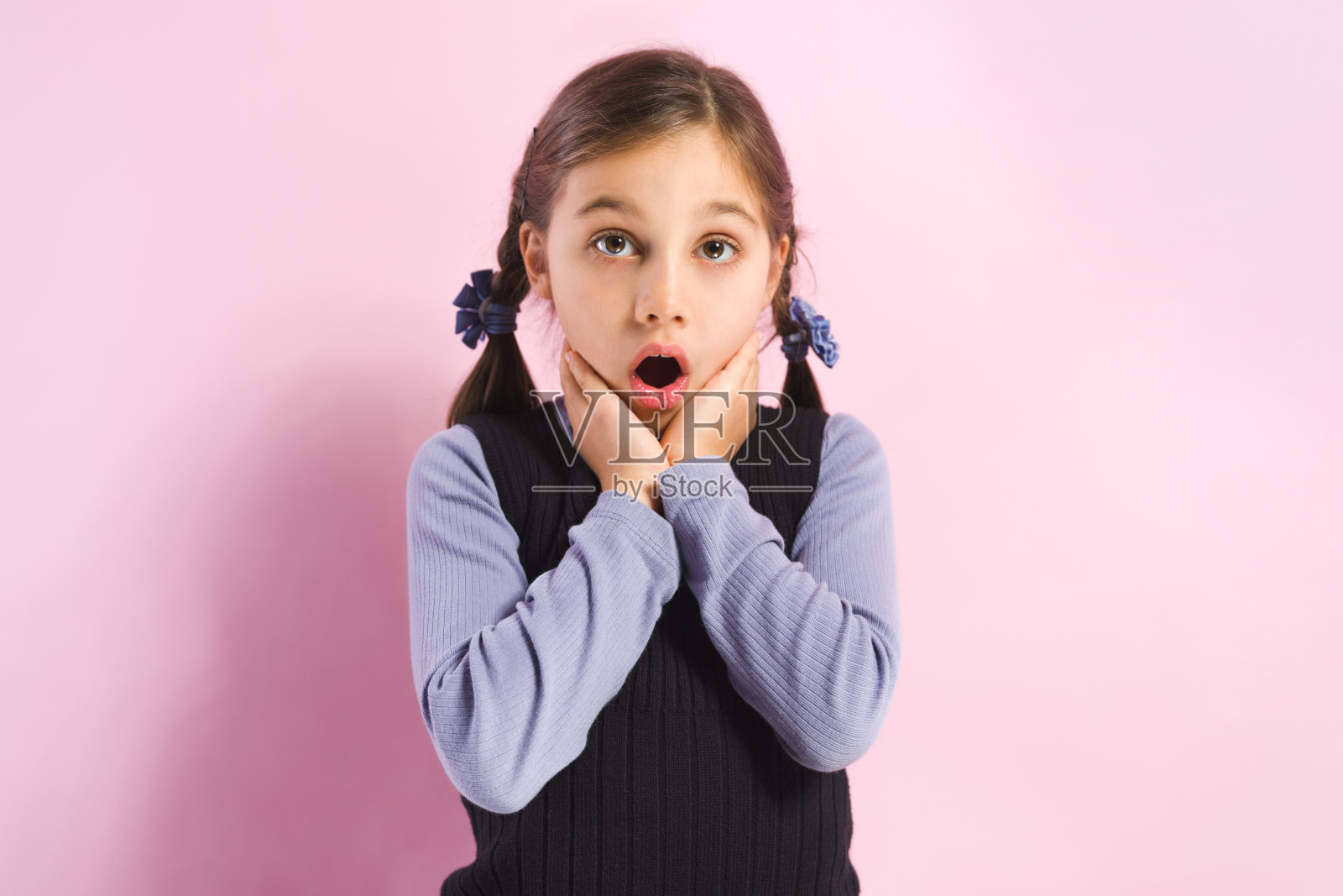 一个惊讶的小女孩的肖像在粉红色的背景照片摄影图片