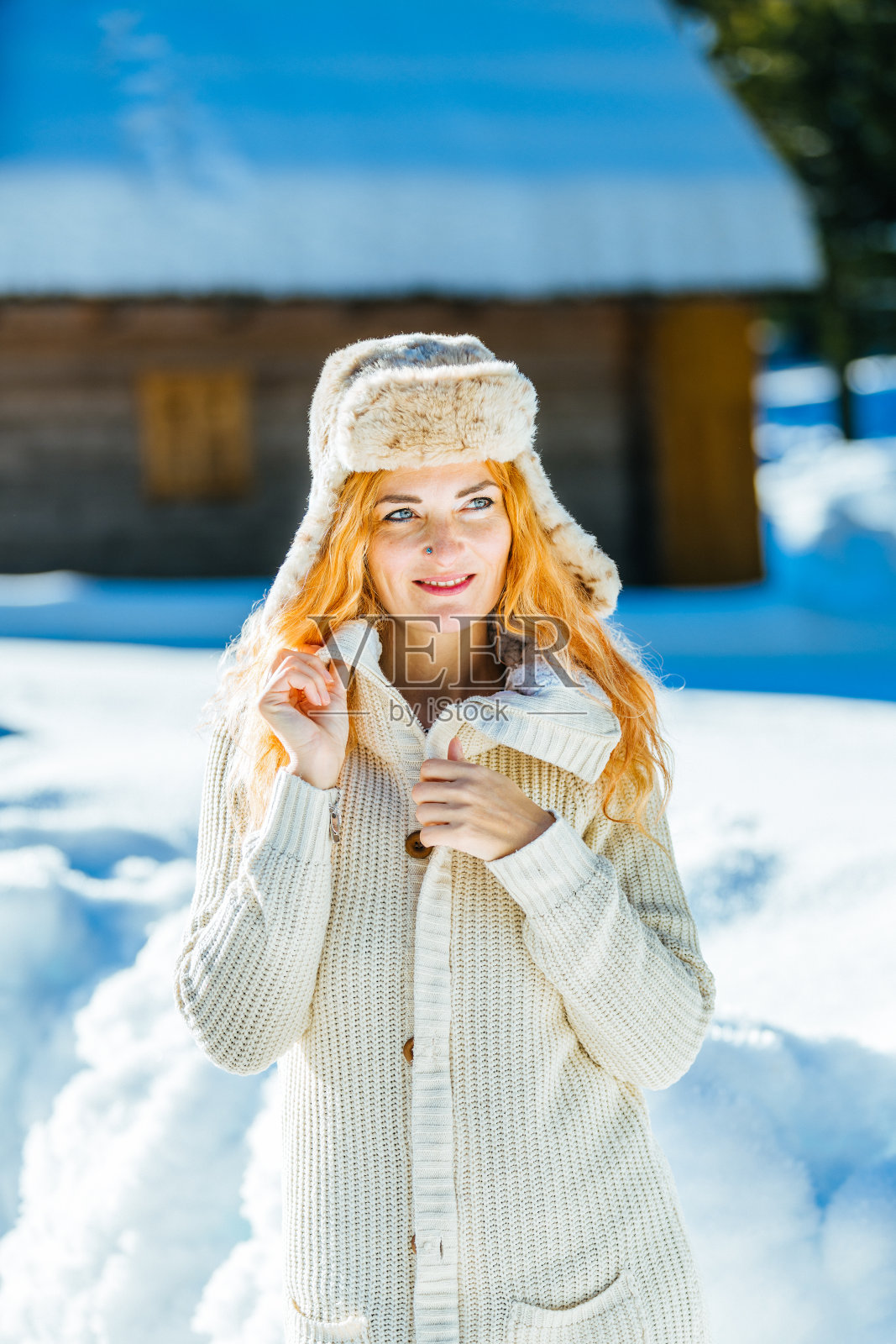快乐的女人，在冬天森林附近的白雪皑皑的草地上照片摄影图片