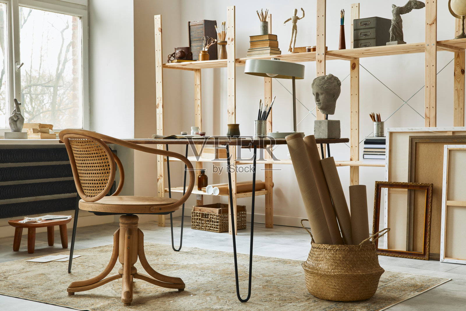 独特的艺术家工作空间内部时尚的书桌，木制画架，书架，艺术品，绘画配件，装饰和优雅的个人物品。艺术家的现代工作室。模板。照片摄影图片