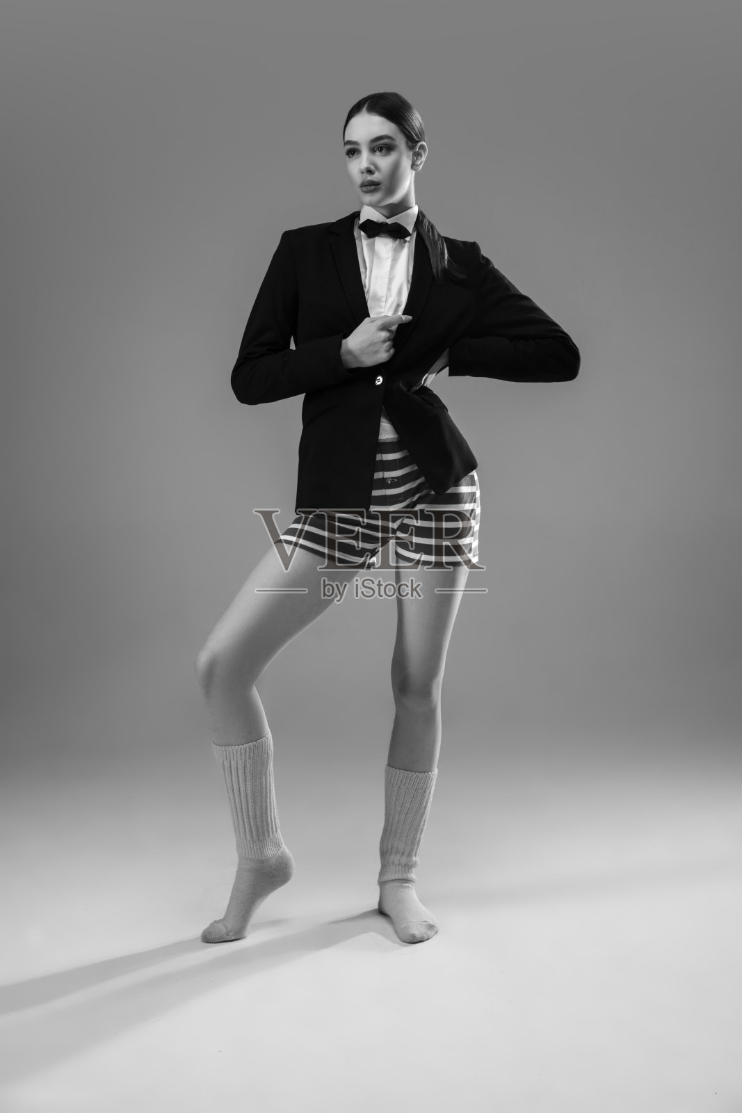 年轻、时尚、时髦的女性穿着夹克和袜子在家工作。保温期间的时尚是冠状病毒大流行的原因照片摄影图片