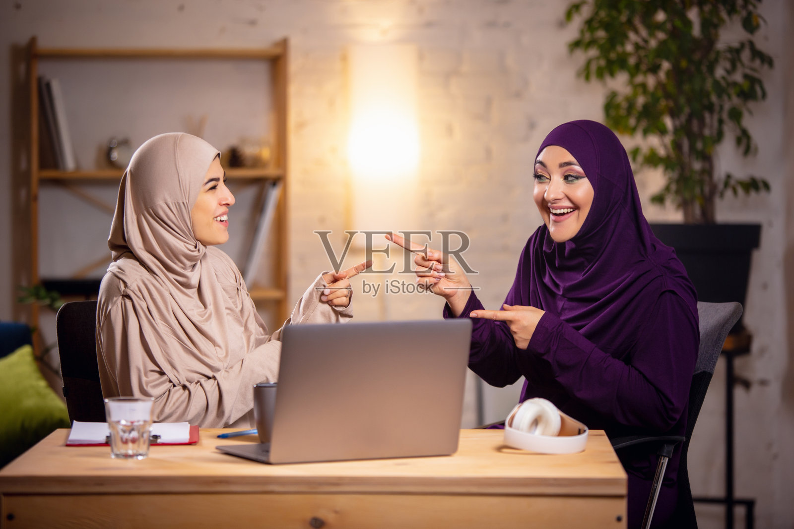 两个快乐的穆斯林妇女在家里上课，在电脑附近学习，进行在线教育照片摄影图片