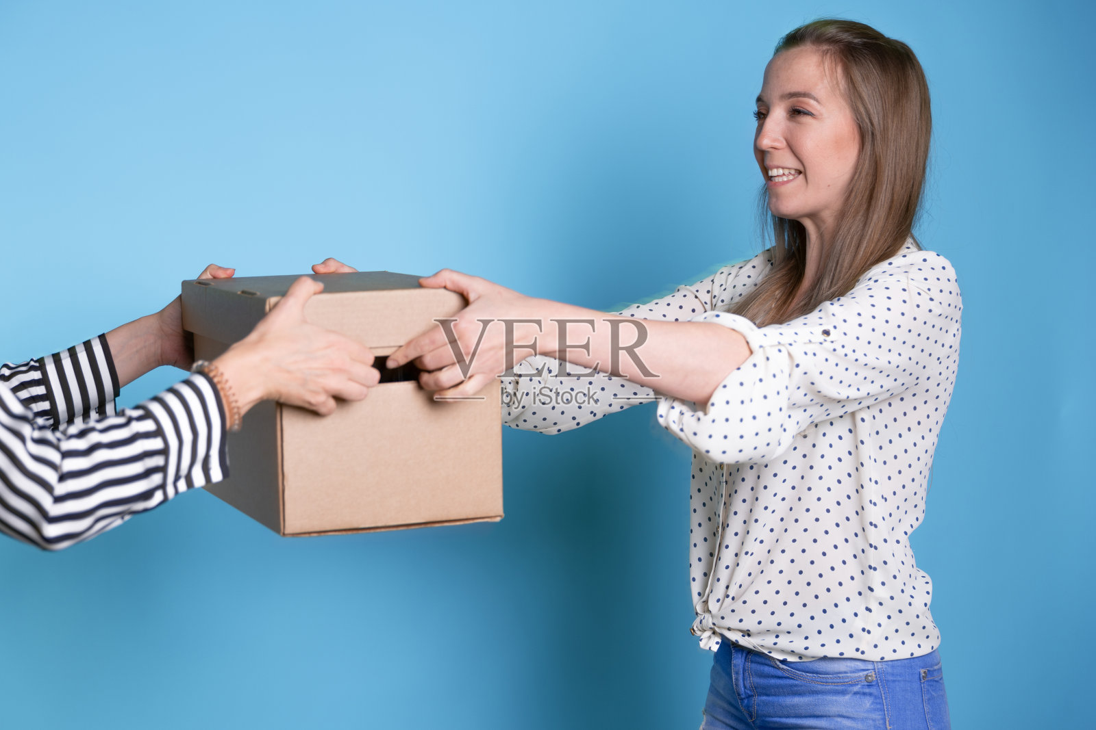 你将一个装有包裹的盒子从一只手传到另一只手，然后发送、转移和接收，一位年轻女士将收到一份礼物或快递。照片摄影图片