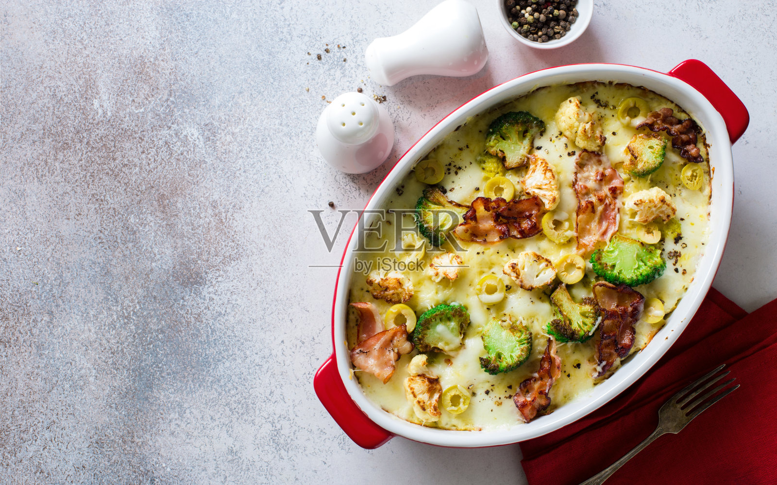 灰色的石头桌上放着西兰花、花椰菜、绿橄榄、培根和奶酪自制砂锅菜照片摄影图片