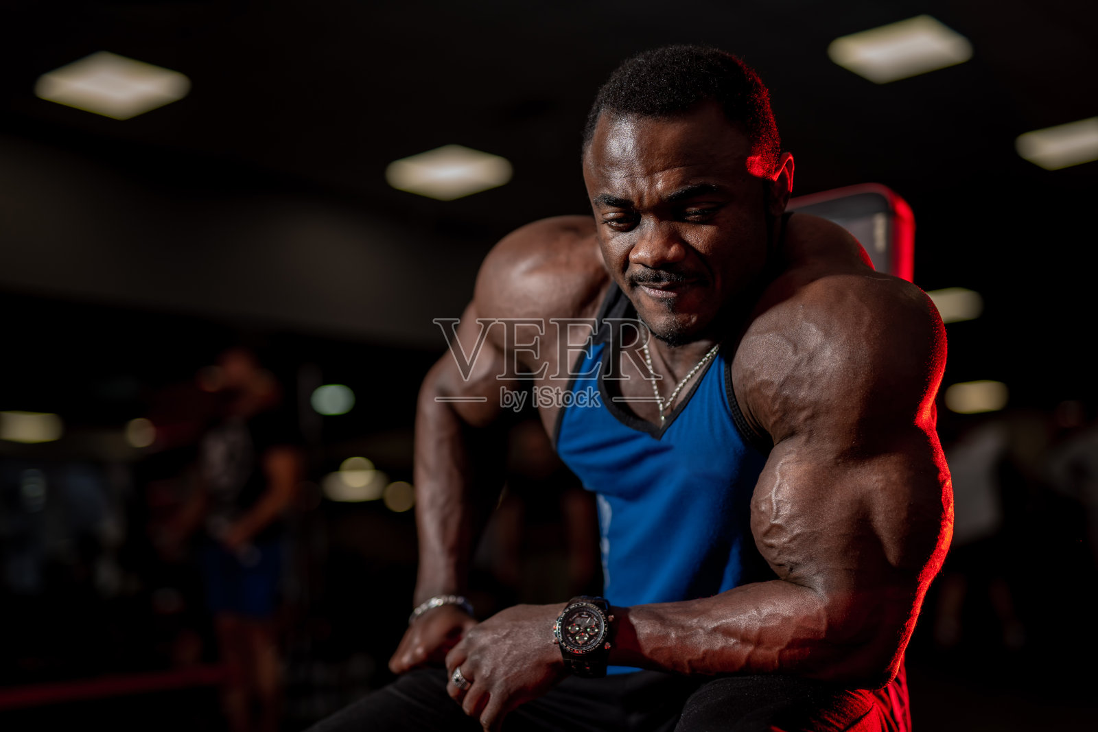 非裔美国健美运动员在健身房对着镜头摆姿势，肌肉发达，双手强壮。模糊的背景。照片摄影图片