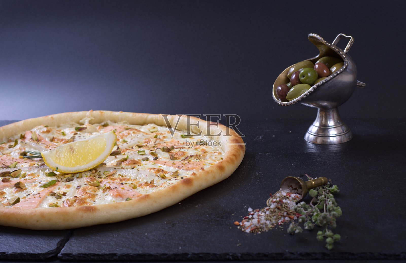 黑色的石头桌子上放着一个漂亮的披萨，上面有西红柿、肉和奶酪照片摄影图片