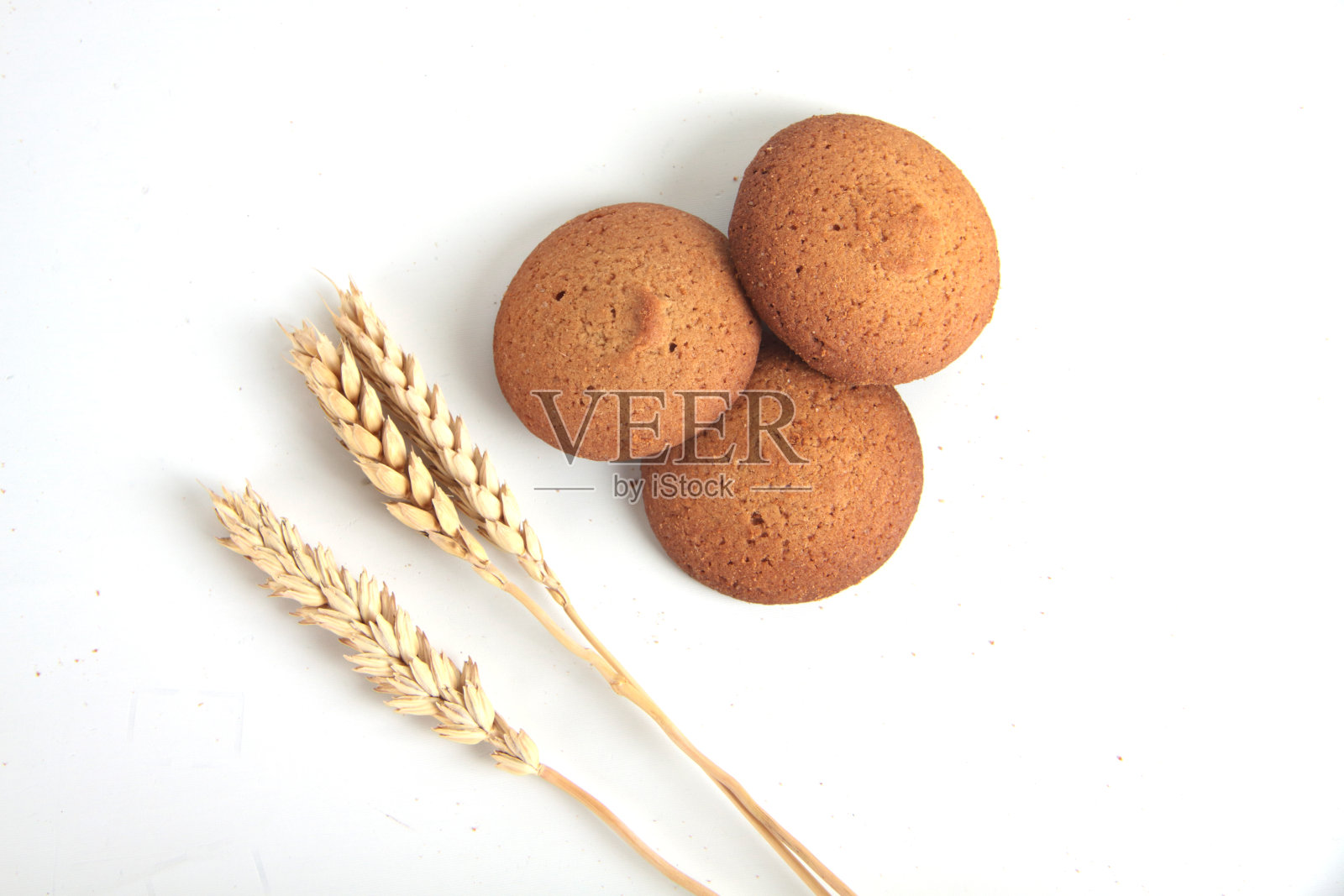一堆燕麦饼干和小麦穗孤零零地躺在白色的背景上照片摄影图片