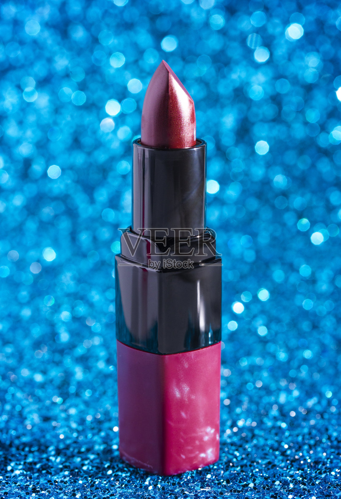 一管淡紫色的口红在蓝色闪光的背景上照片摄影图片