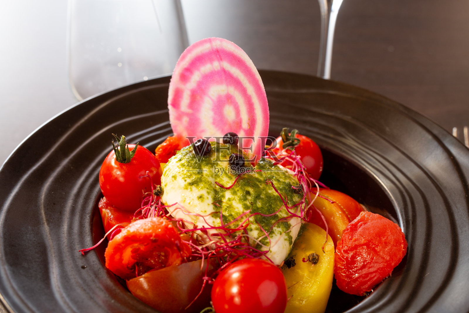黑色盘子里有鱼和西红柿照片摄影图片