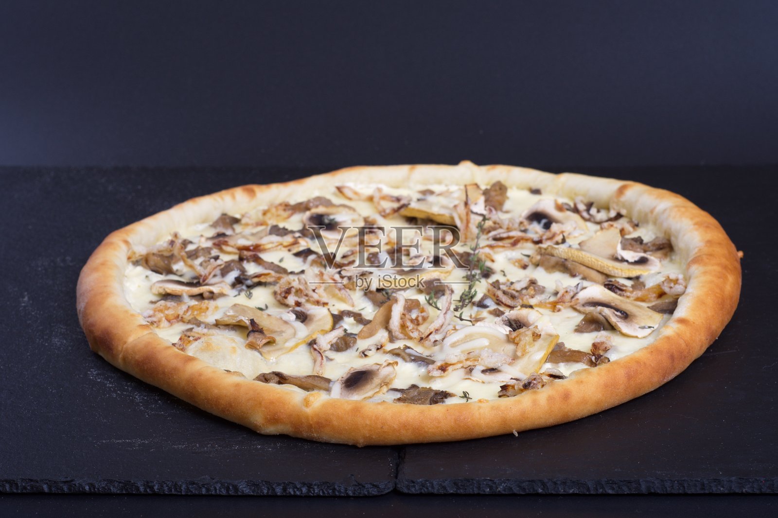 黑色的石头桌子上放着一个漂亮的披萨，上面有西红柿、肉和奶酪照片摄影图片