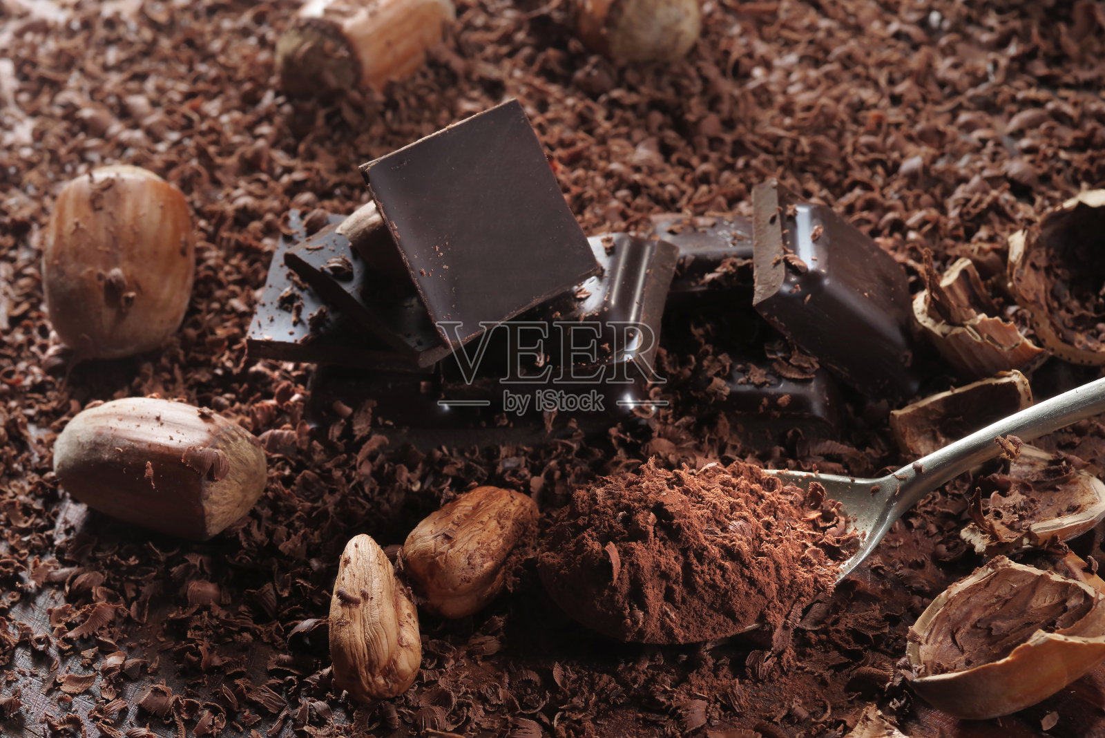 黑巧克力和榛子。黑色的餐桌上放着碎巧克力照片摄影图片