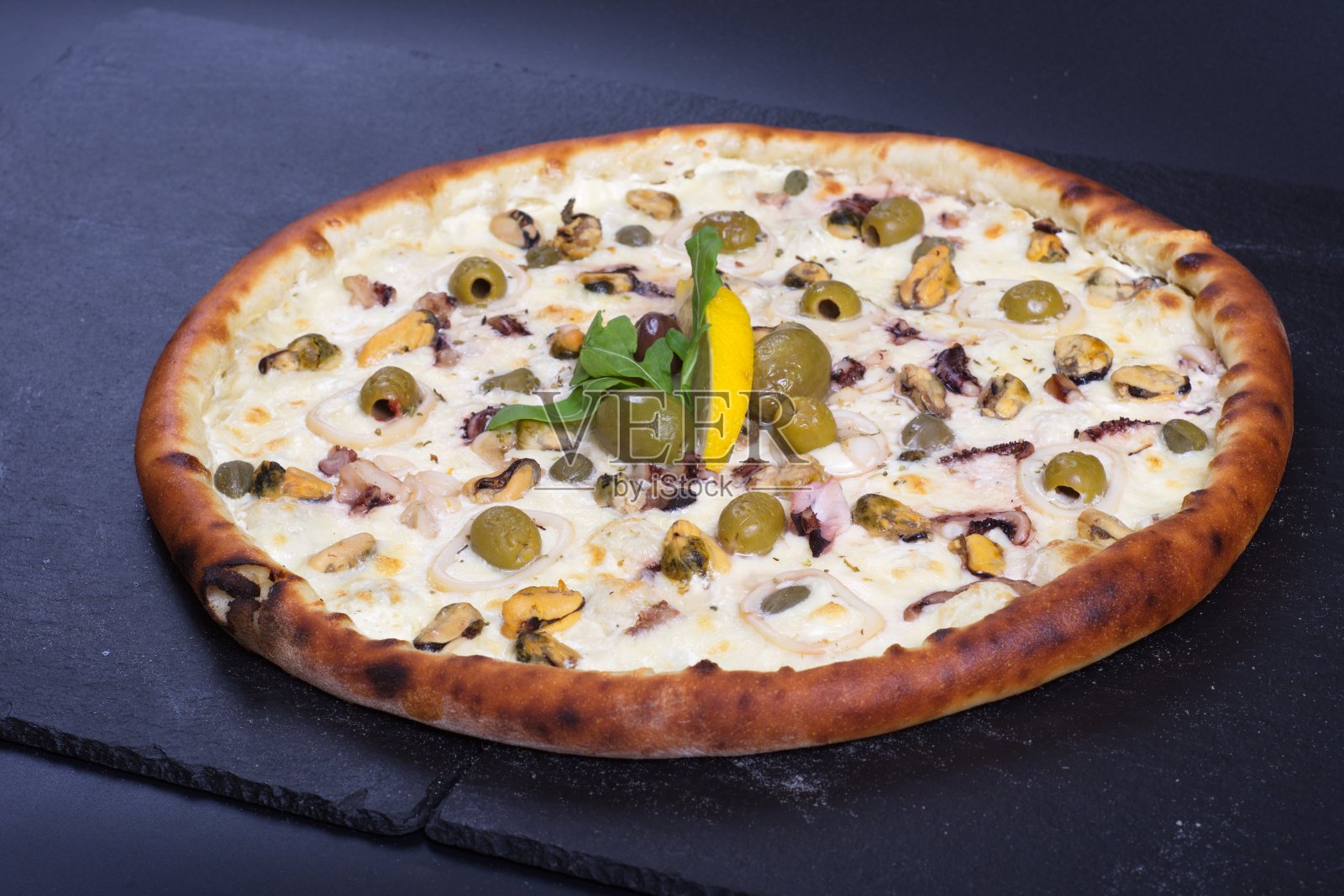 黑色的石头桌子上放着一个漂亮的披萨，上面有西红柿、肉和奶酪照片摄影图片