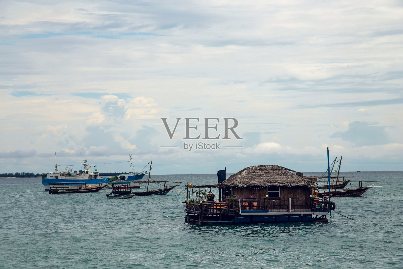 在温暖阳光明媚的日子里，在海边没有乘客的船屋和小船照片摄影图片