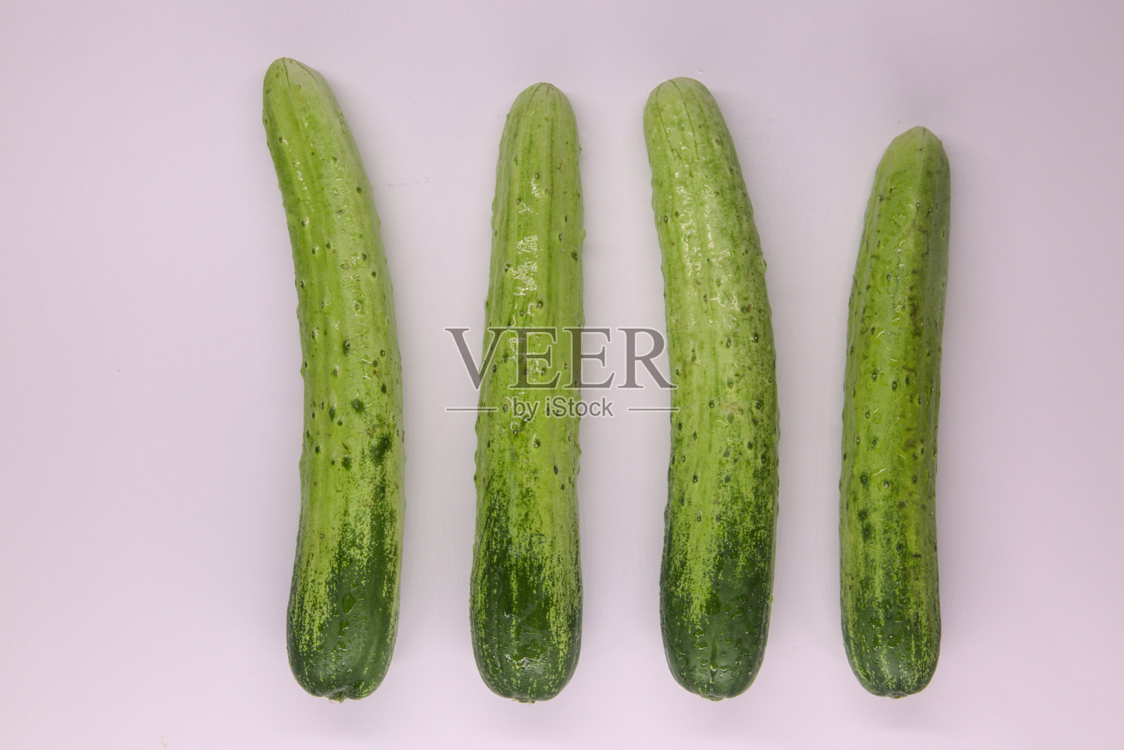 4个成熟的绿色黄瓜在粉红色的背景上，孤立照片摄影图片