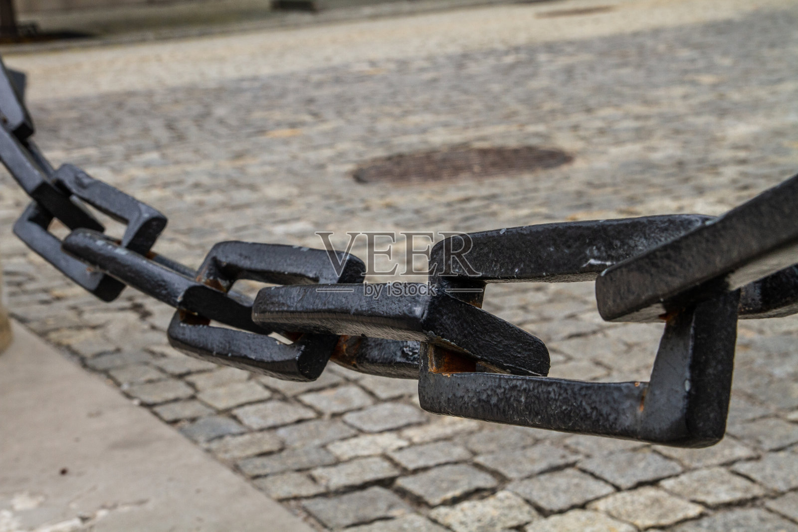 巨大的黑色链条在人行道的背景上。照片摄影图片