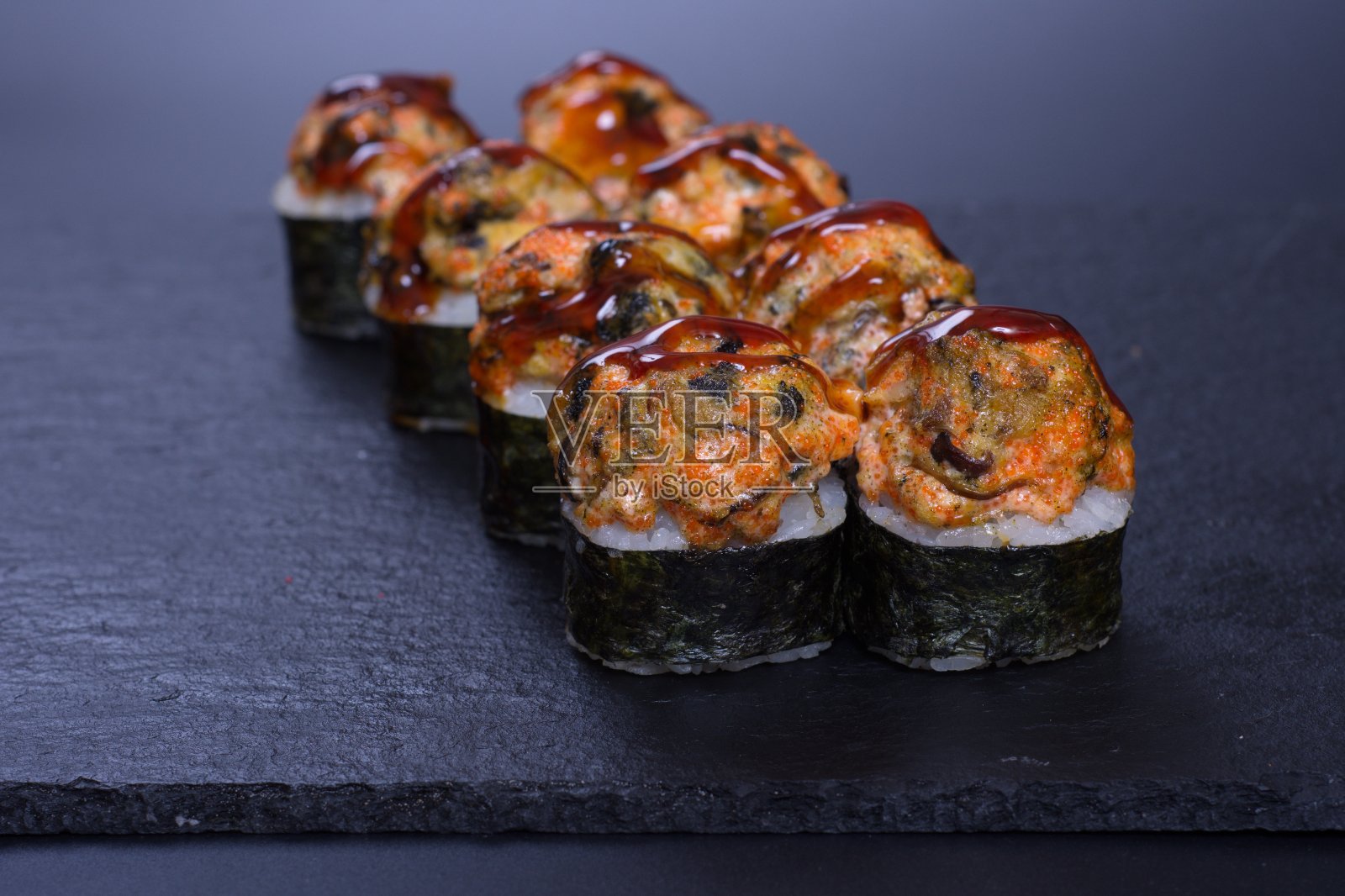 黑色的桌子上放着五颜六色的卷饼，里面有奶酪、米饭、海藻和鱼照片摄影图片