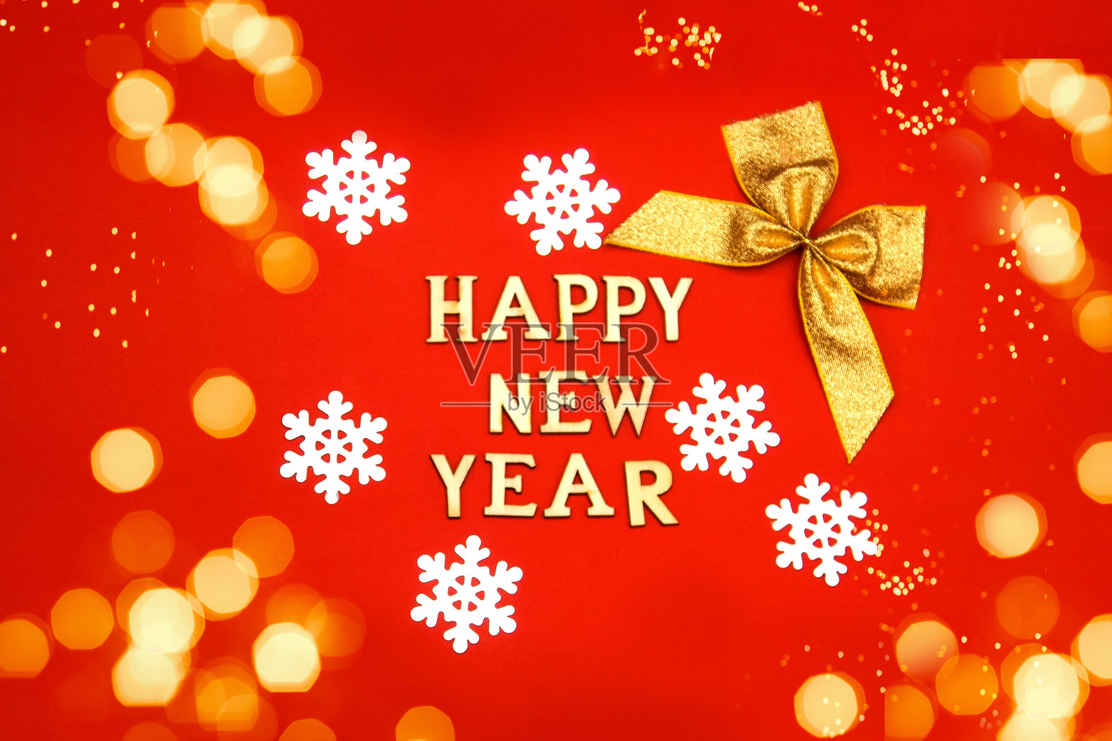 题词新年快乐木制字母在红色的背景与雪花和弓，bokeh。新年贺卡、横幅照片摄影图片