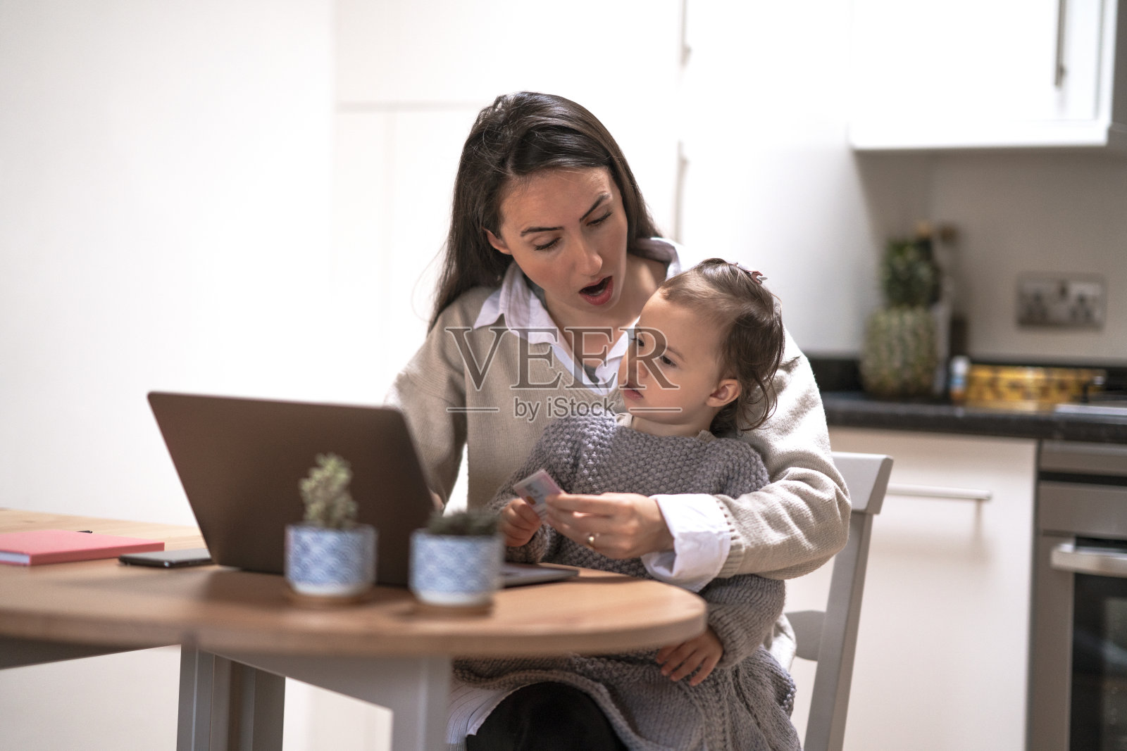 年轻的妈妈在工作，被她的小宝贝在网上购物惊呆了照片摄影图片