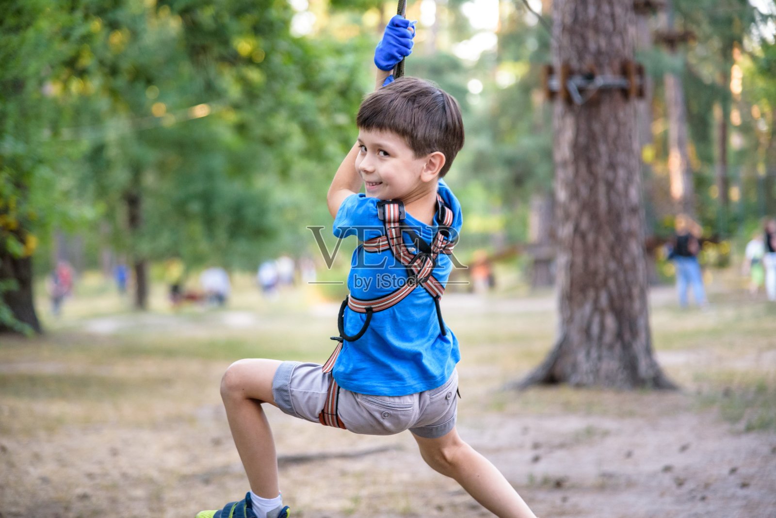 微笑的男孩骑着滑索。快乐的孩子在滑索上。这孩子通过了绳索障碍赛照片摄影图片