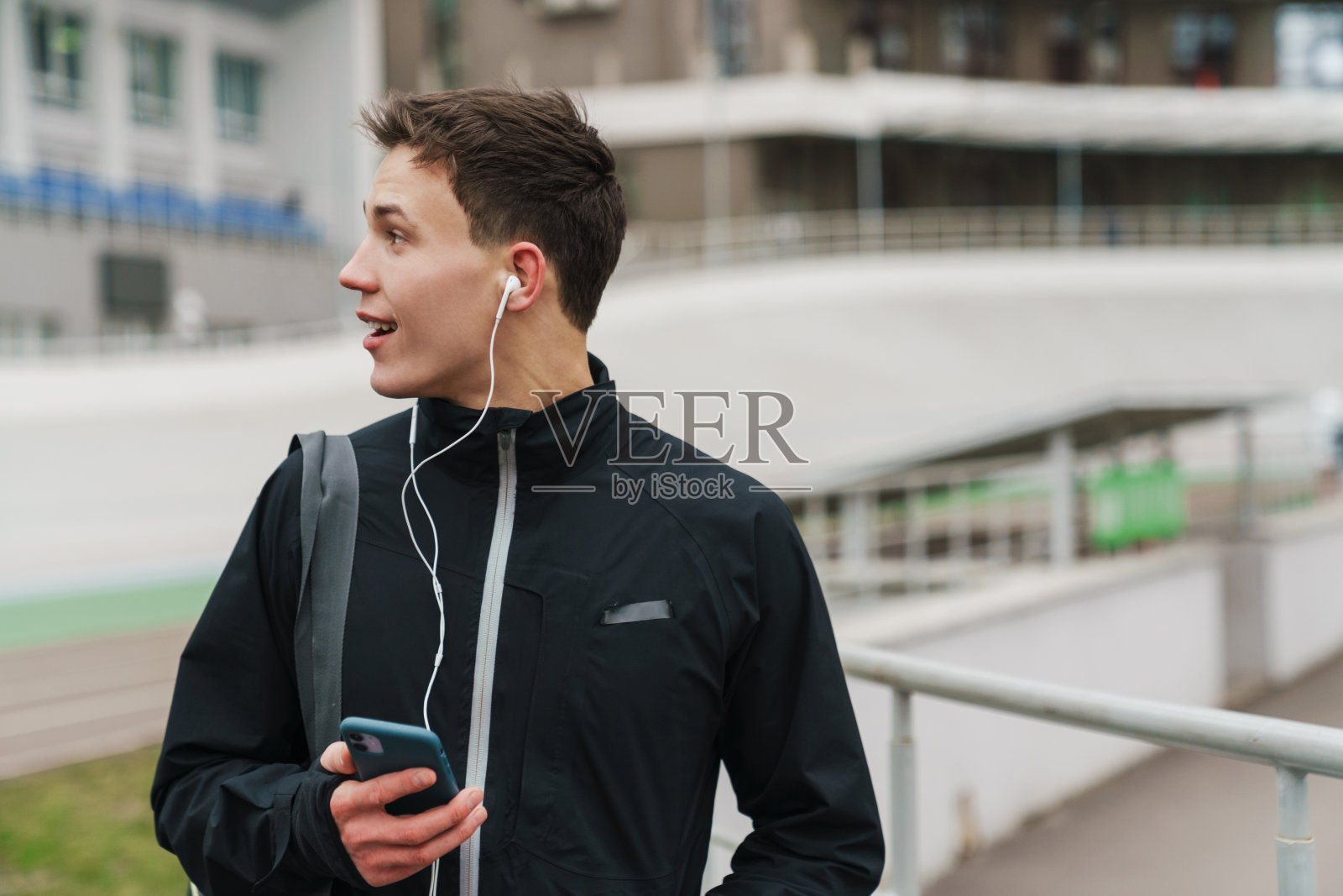 英俊快乐的运动员用耳机和手机听音乐照片摄影图片