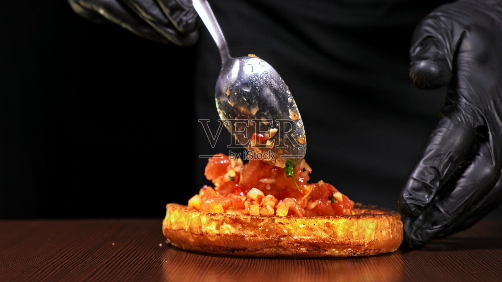 手工汉堡在黑色背景下烹饪。包括:沙司，生菜，红洋葱，泡菜，奶酪，辣椒青椒，面包，大理石肉牛肉。照片摄影图片