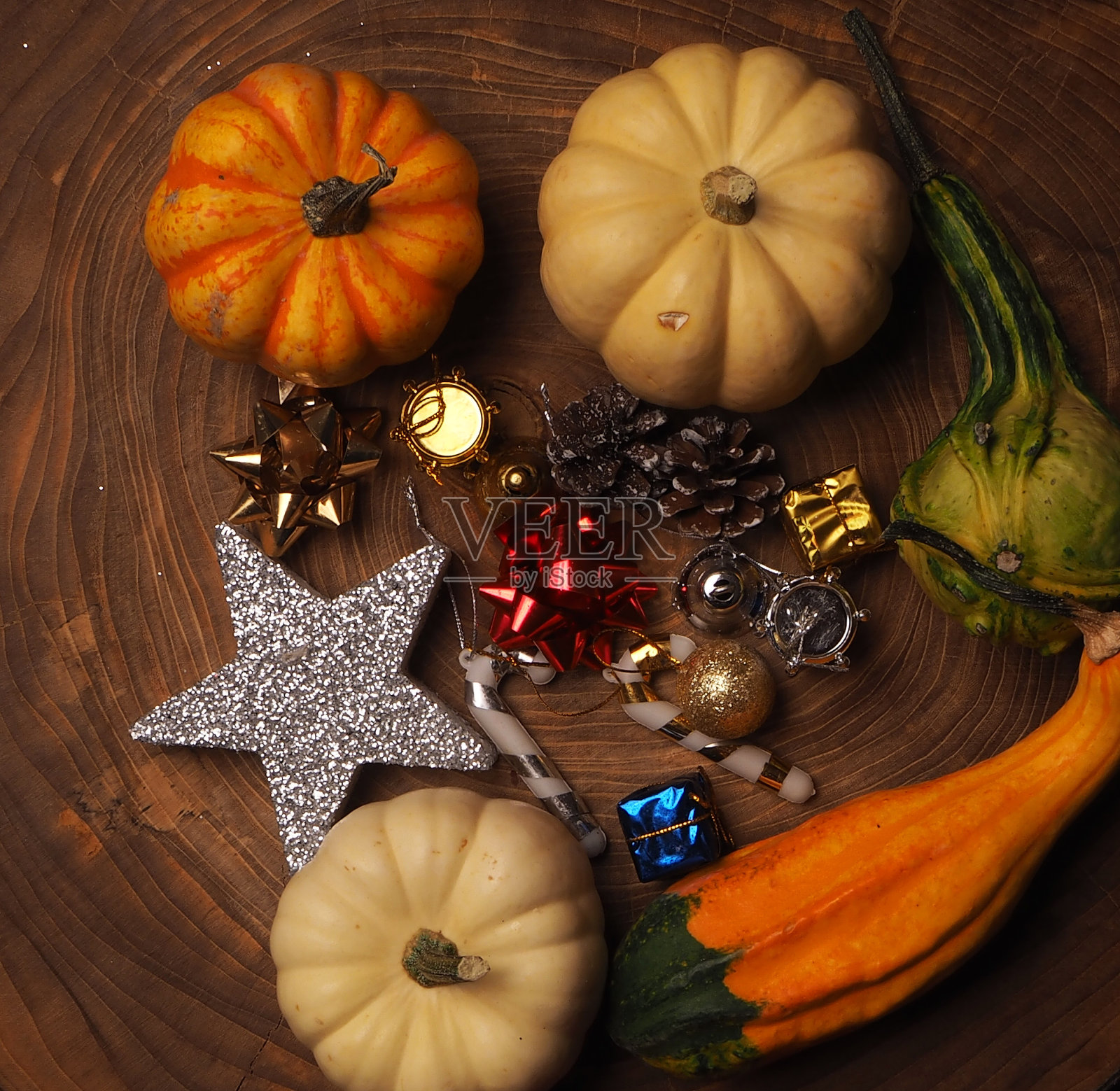 木制树桩上五颜六色的圣诞装饰。五颜六色的小南瓜和干树叶照片摄影图片