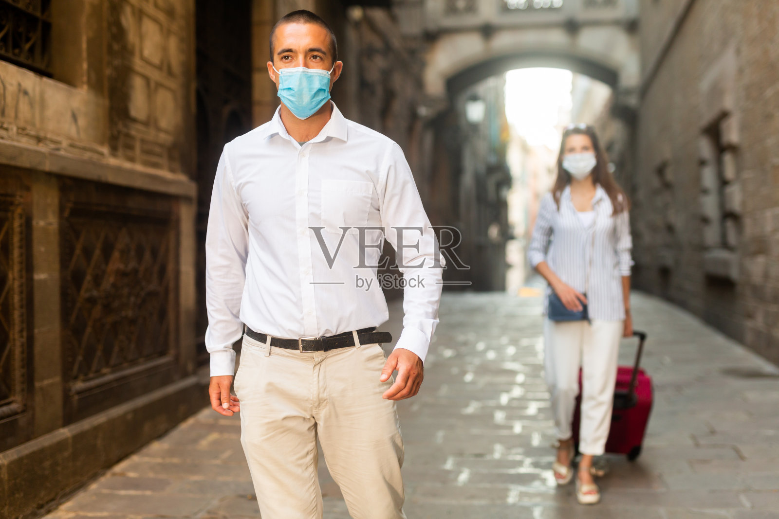 戴着医用口罩的年轻人走在城市街道上照片摄影图片