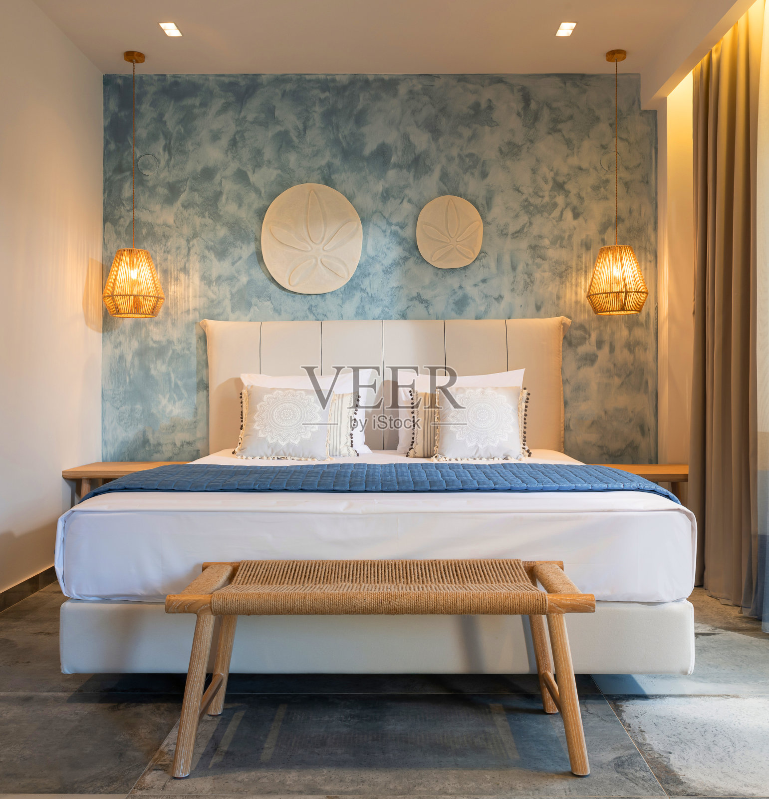 前视图的现代卧室室内在航海风格与蓝色装饰灰泥墙，柳条家具，天花板木制灯，白色软床照片摄影图片