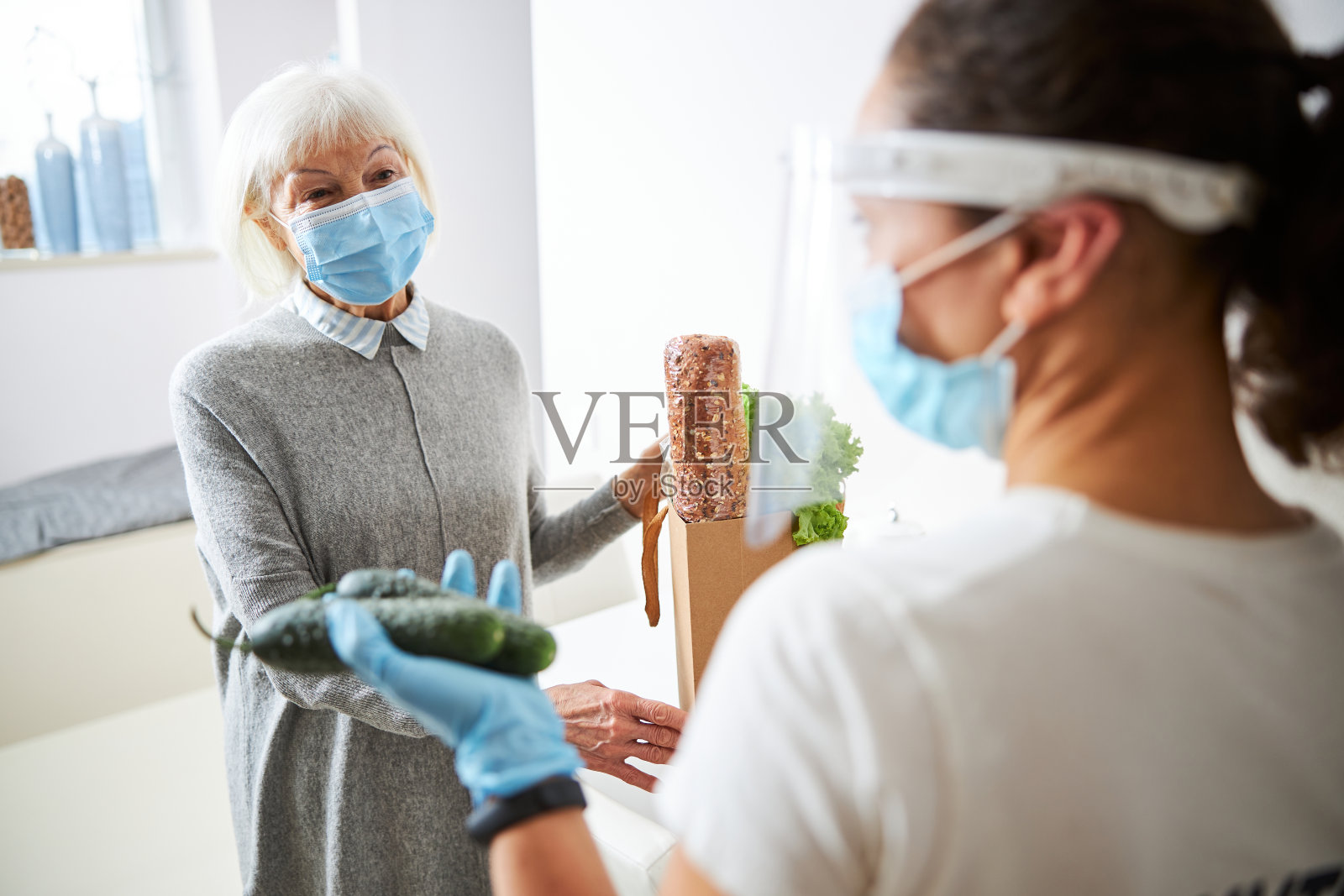 金发女郎和年轻的看护者站在厨房里照片摄影图片