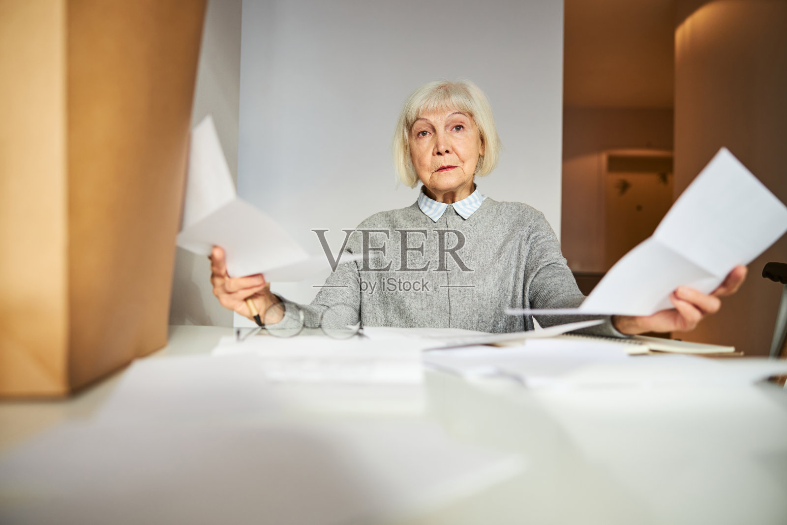 一个沮丧的领养老金的人拿着文件坐在桌子旁照片摄影图片