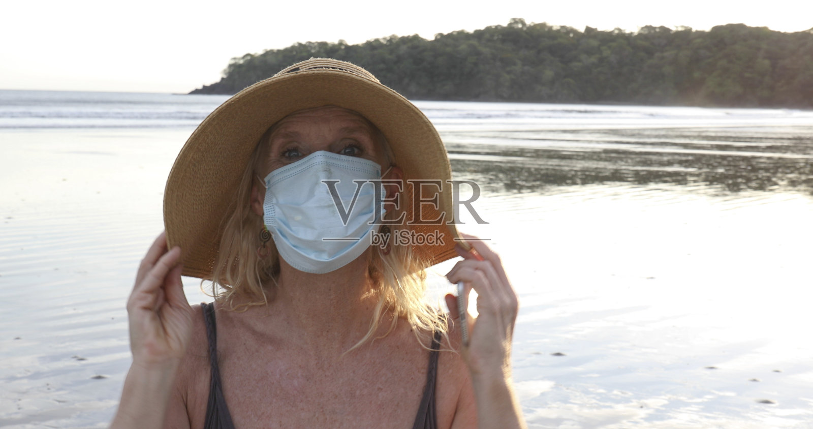 戴口罩的女人在日出时分于海滩放松照片摄影图片