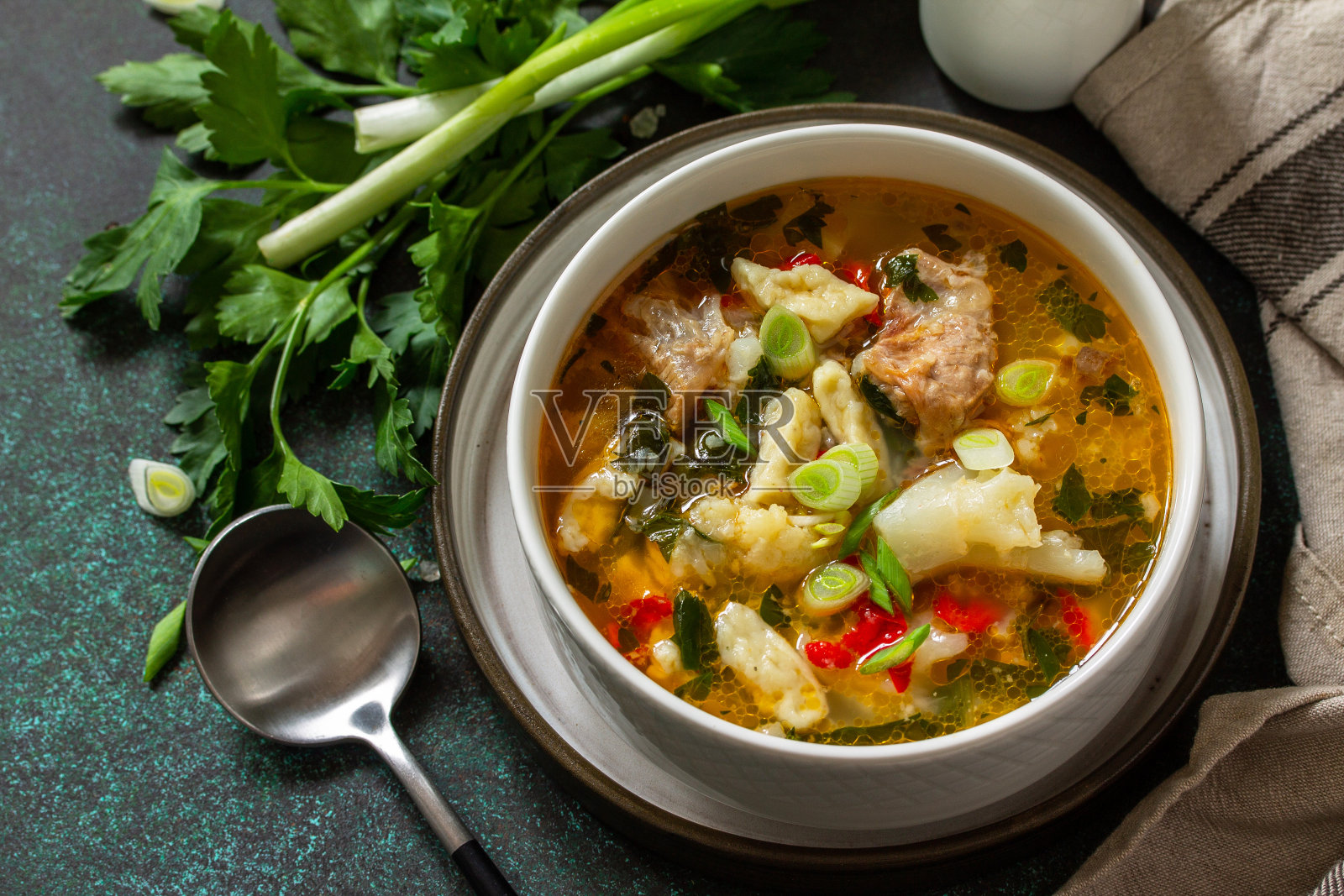 热腾腾的美味牛肉汤。黑色的石头背景上自制的肉、蔬菜和汤圆。照片摄影图片