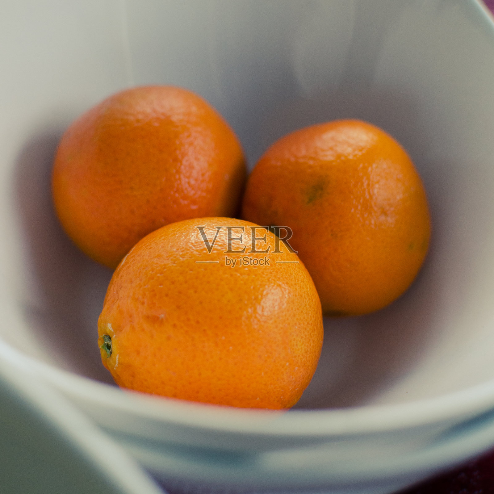 三个新鲜的橙子在一个白色的碗里照片摄影图片