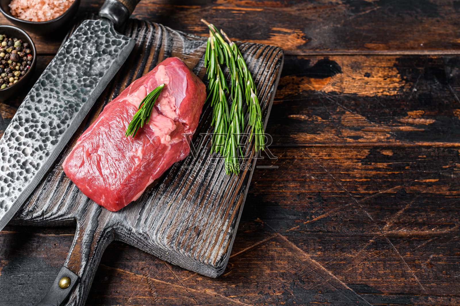 生羊排放在木板上，配上香草。深色木制背景。前视图。本空间照片摄影图片