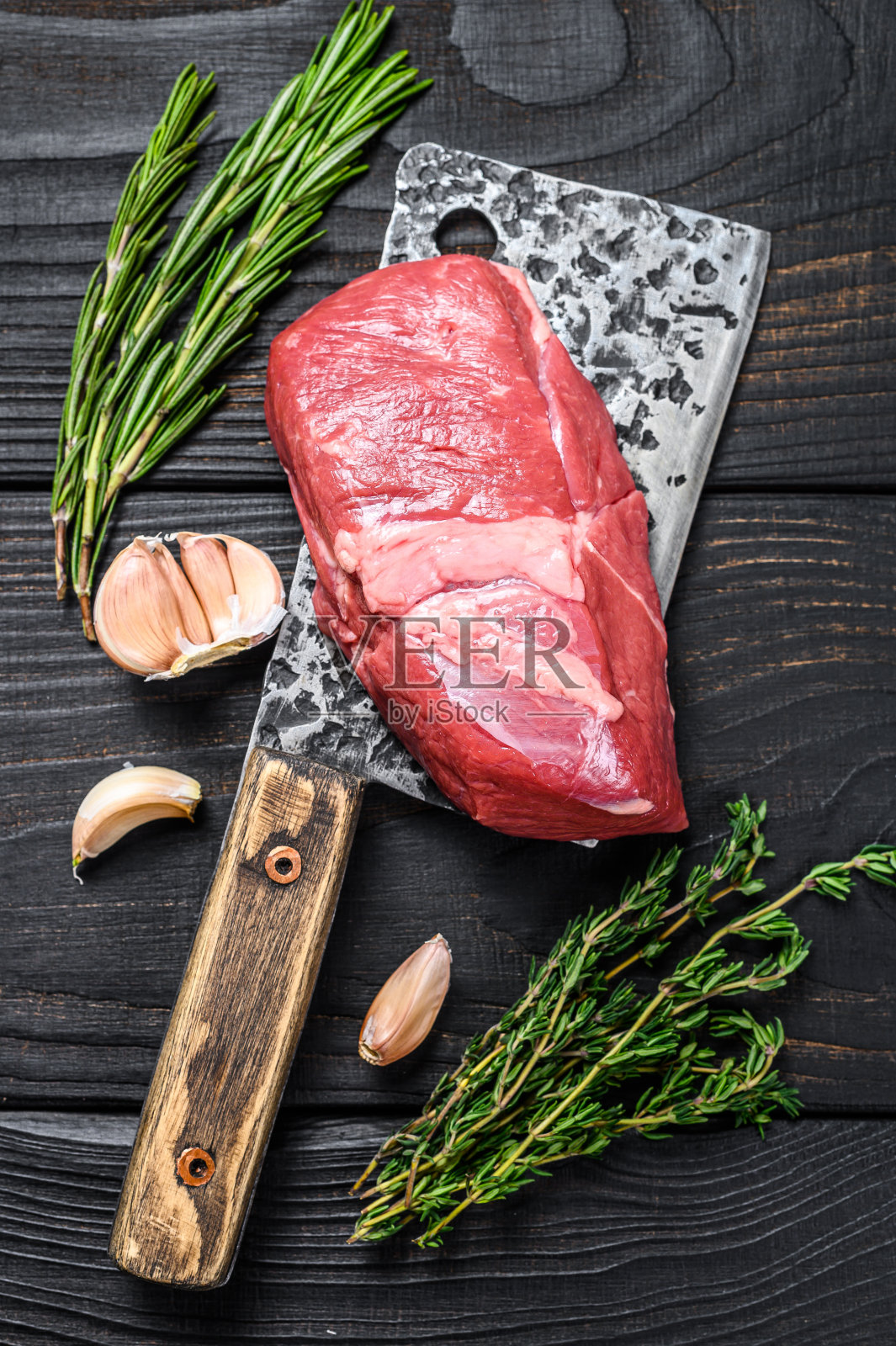 用切肉刀切的生羊肉里脊。黑色木制背景。俯视图照片摄影图片