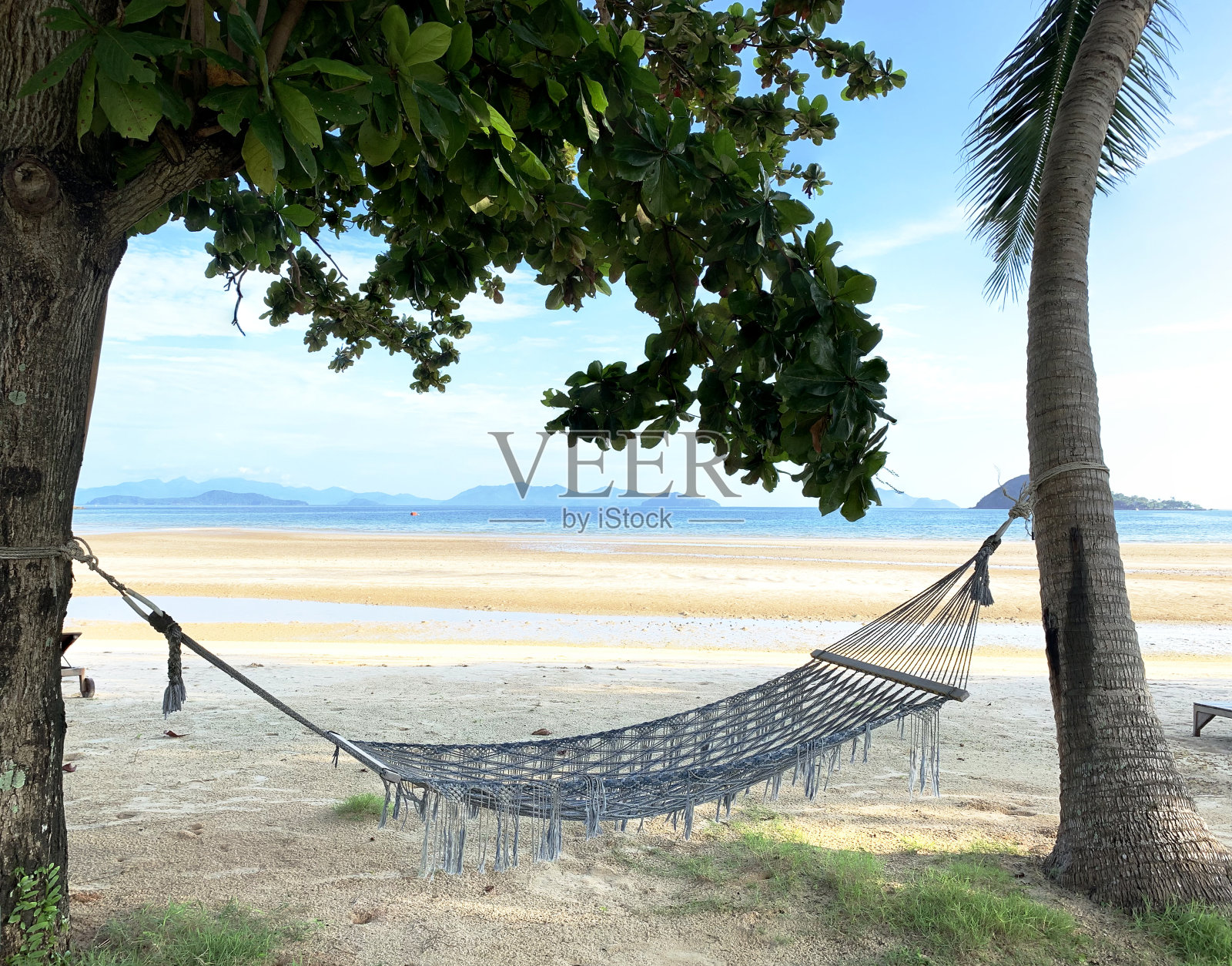 一个美丽宁静的下午，放松的海边气氛。在树荫下的布质吊床和木制的泳池床，风舒适地吹着，高窑诺伊，特拉特，泰国。照片摄影图片