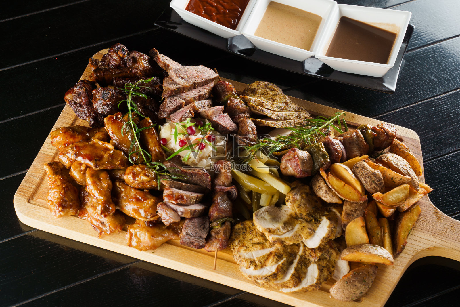 猪肉烤腌羊肉串。烧烤美味的肉在黑色的盘子里。土豆、肉和香肠。照片摄影图片