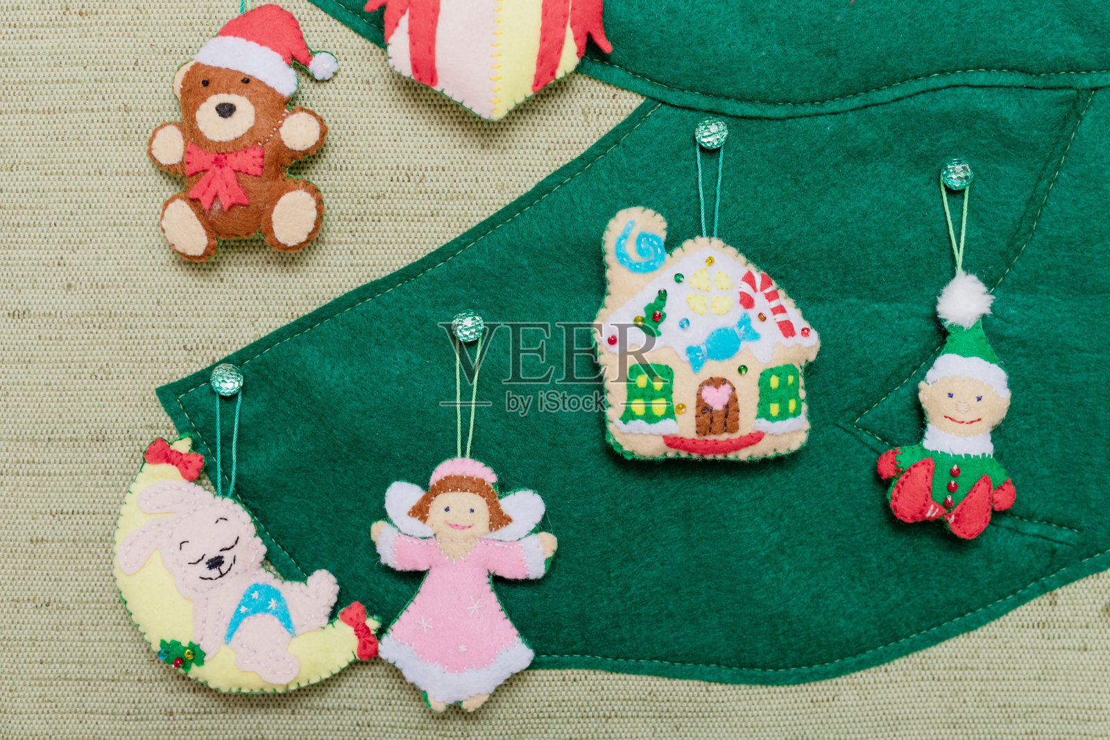 绿色的毛毡圣诞树的一部分，上面挂着圣诞玩具:仙女，球，雪花，兔子。创意圣诞艺术概念。照片摄影图片