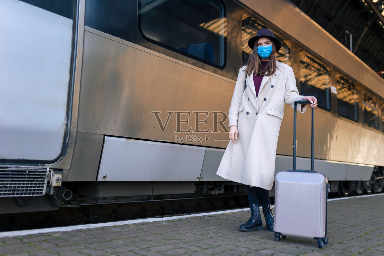 火车站的蒙面女游客。大流行期间的旅游概念。公共交通的病毒预防措施照片摄影图片