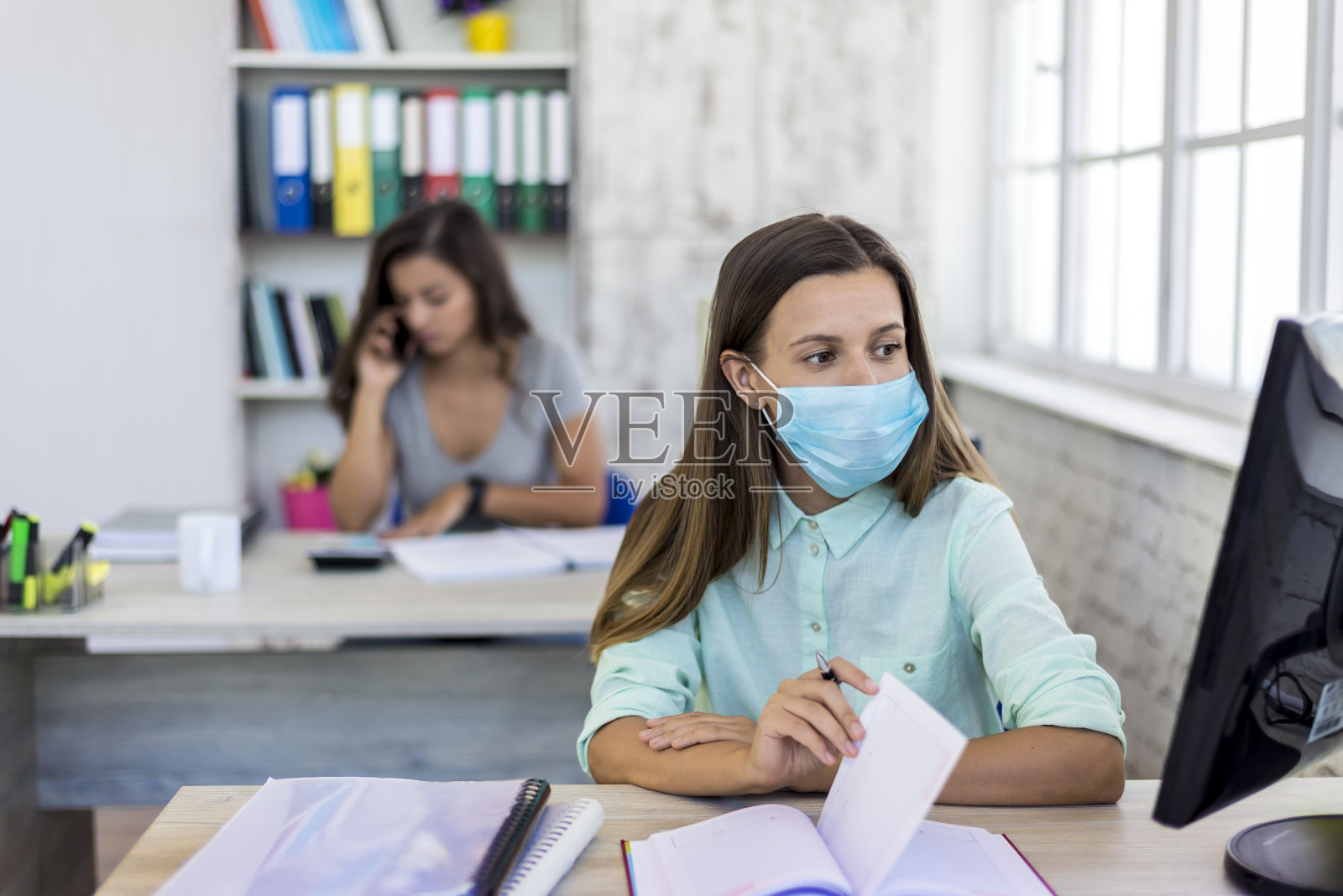 新冠肺炎疫情期间，办公室同事戴着医用口罩工作照片摄影图片