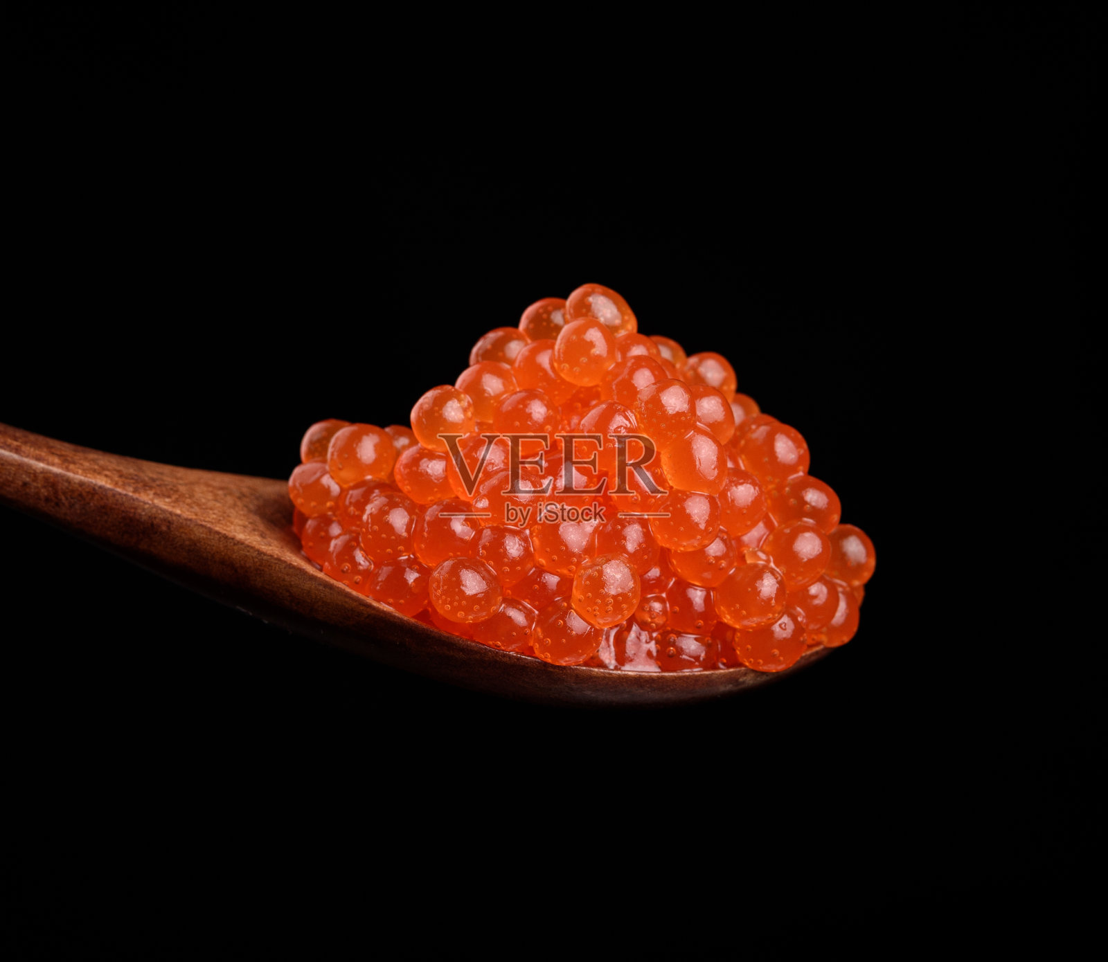 新鲜的红色颗粒鲑鱼鱼子酱放在木勺里，美味又健康的食物照片摄影图片