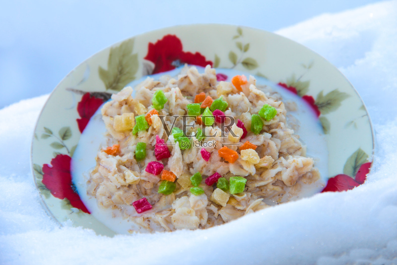 雪中有干果的燕麦粥。稀饭用菠萝染色。照片摄影图片