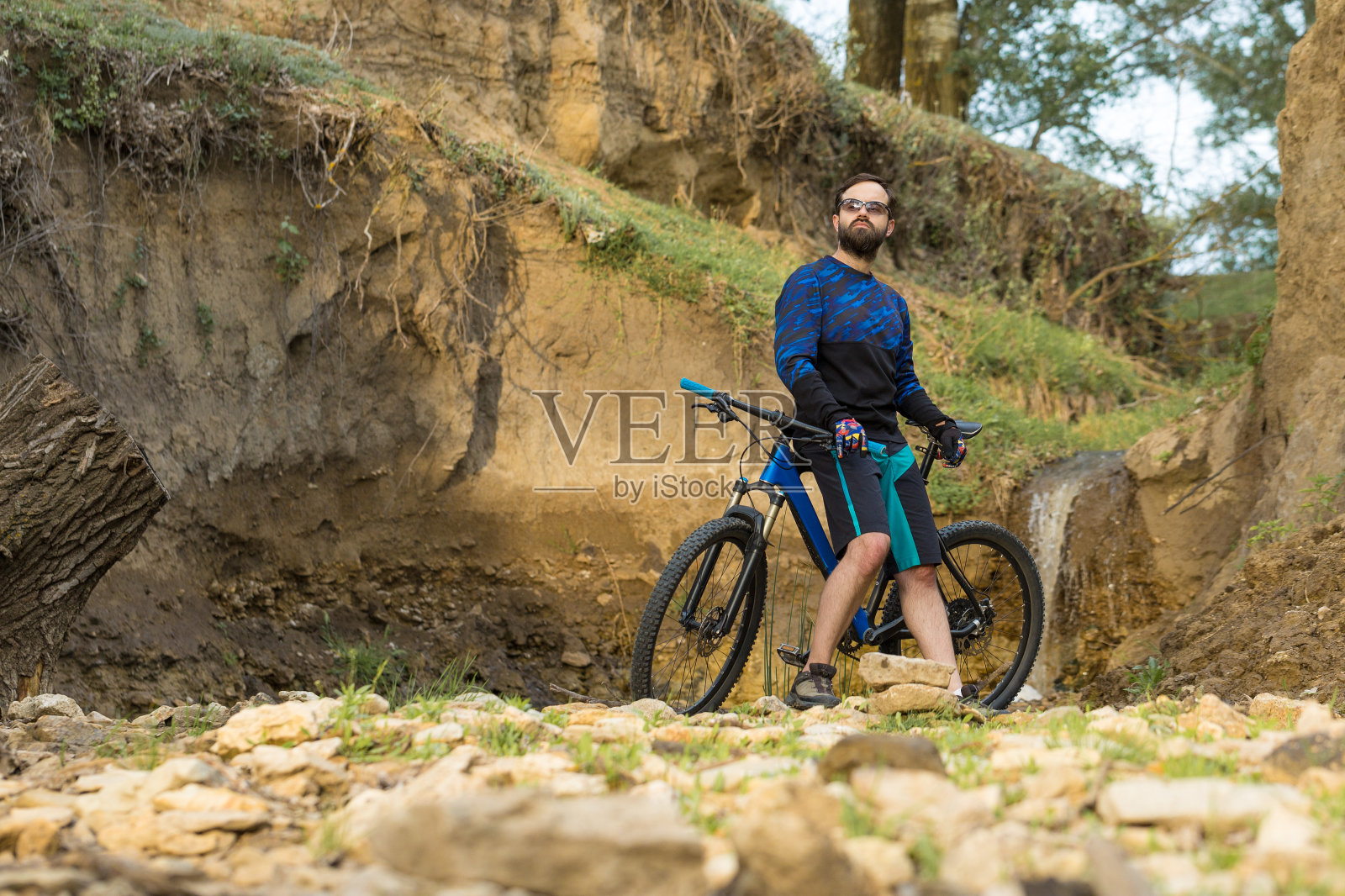骑自行车的人穿着短裤和运动衫，骑着带有空气悬挂叉的现代碳硬尾自行车征服山峰。从山上看，美丽的景色。照片摄影图片