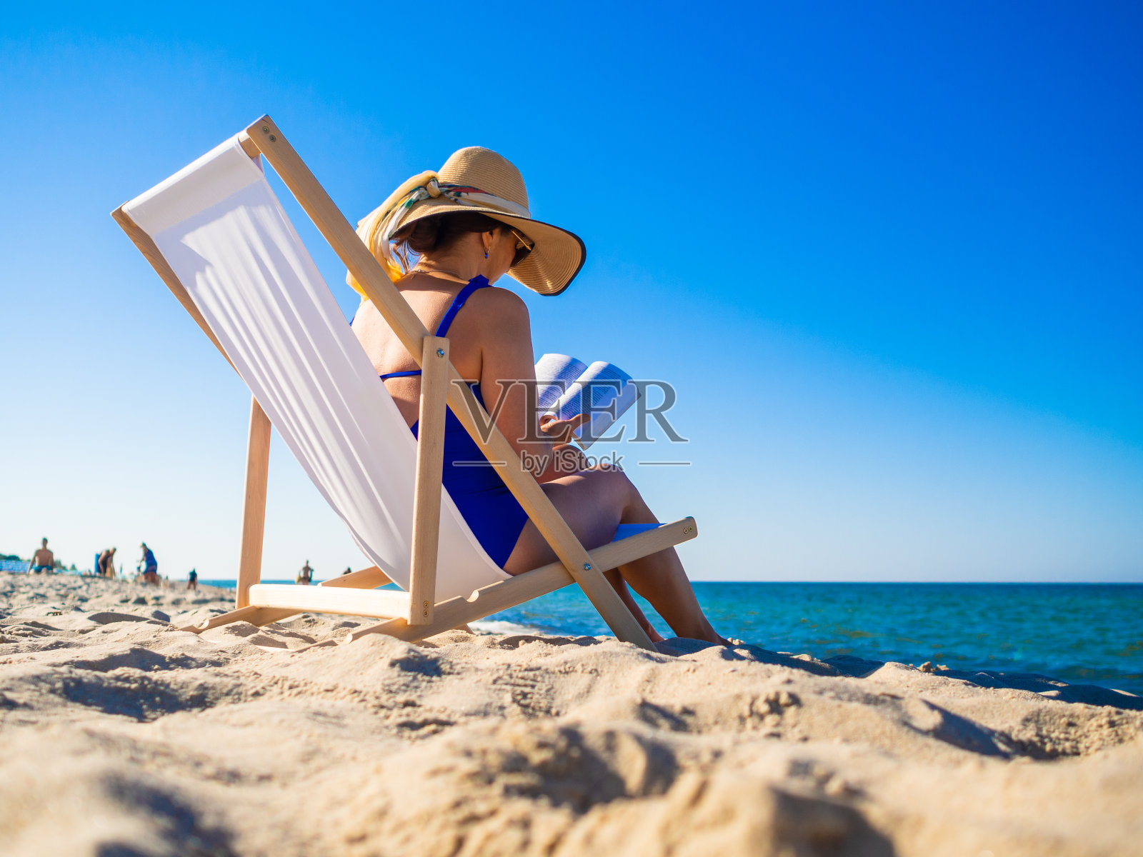 女人放松在沙滩上看书照片摄影图片